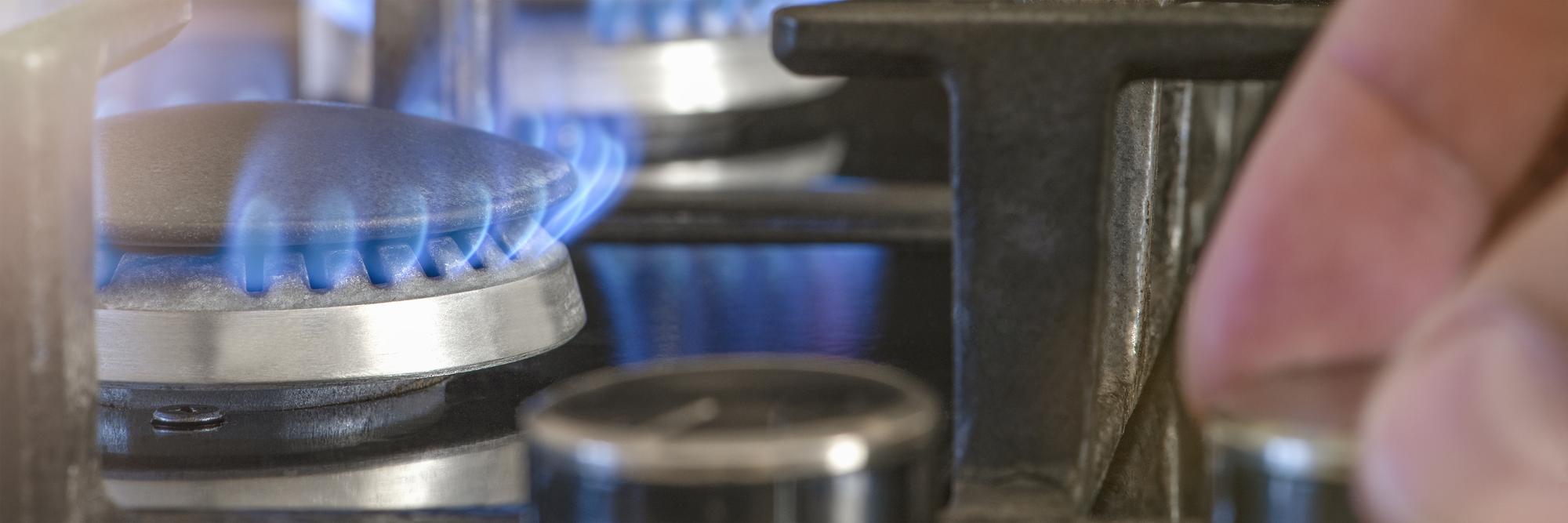 O custo do gás para as necessidades domésticas A mão desaparafusa o queimador a gás na cozinha O uso do gás como aquecimento doméstico no inverno durante a estação fria