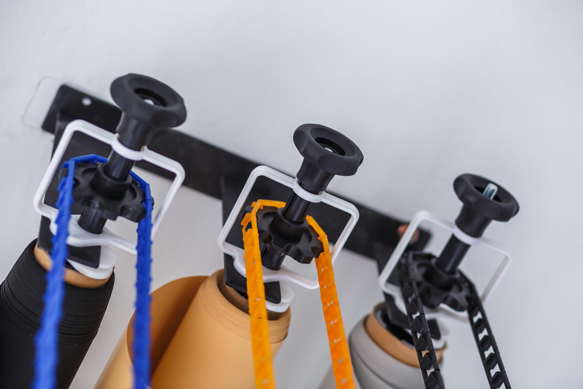 Montagem do sistema de suporte manual para cenários fotográficos em estúdio moderno Rolos de fundos de papel coloridos para estúdio fotográfico pendurados na parede
