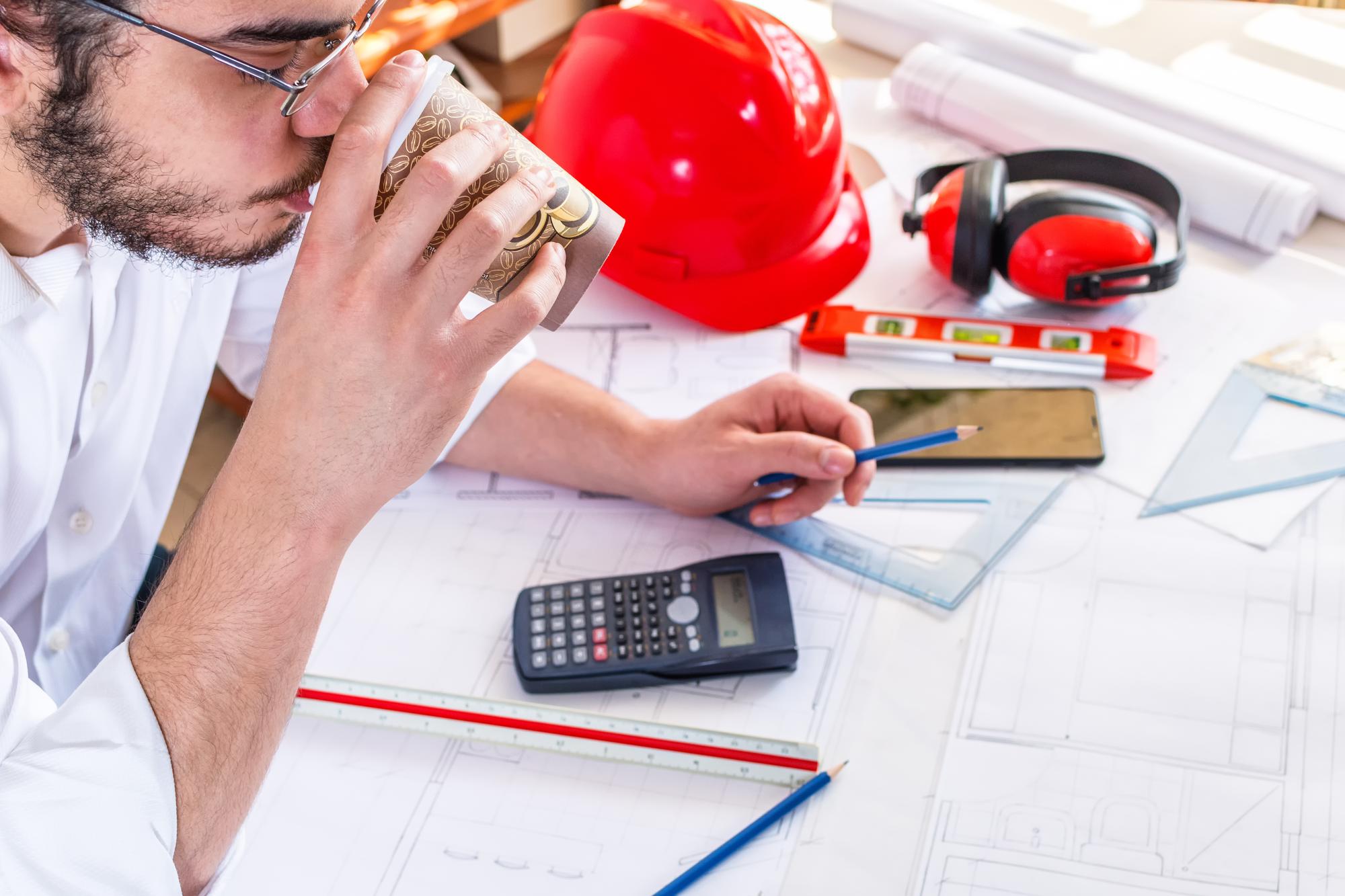 Engenheiro jovem arquiteto bebendo café enquanto trabalhava em planos