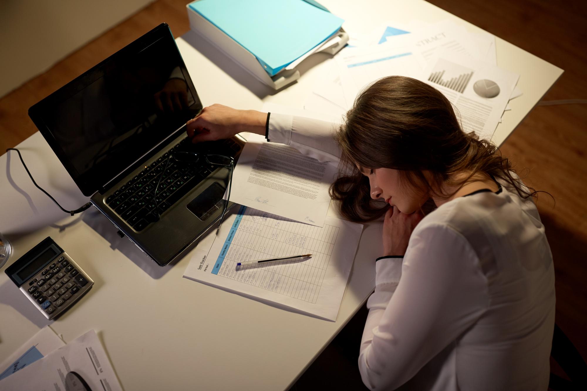 trabalho excessivo prazo de negócios e pessoas conceito mulher cansada com laptop e papéis dormindo na mesa no escritório à noite