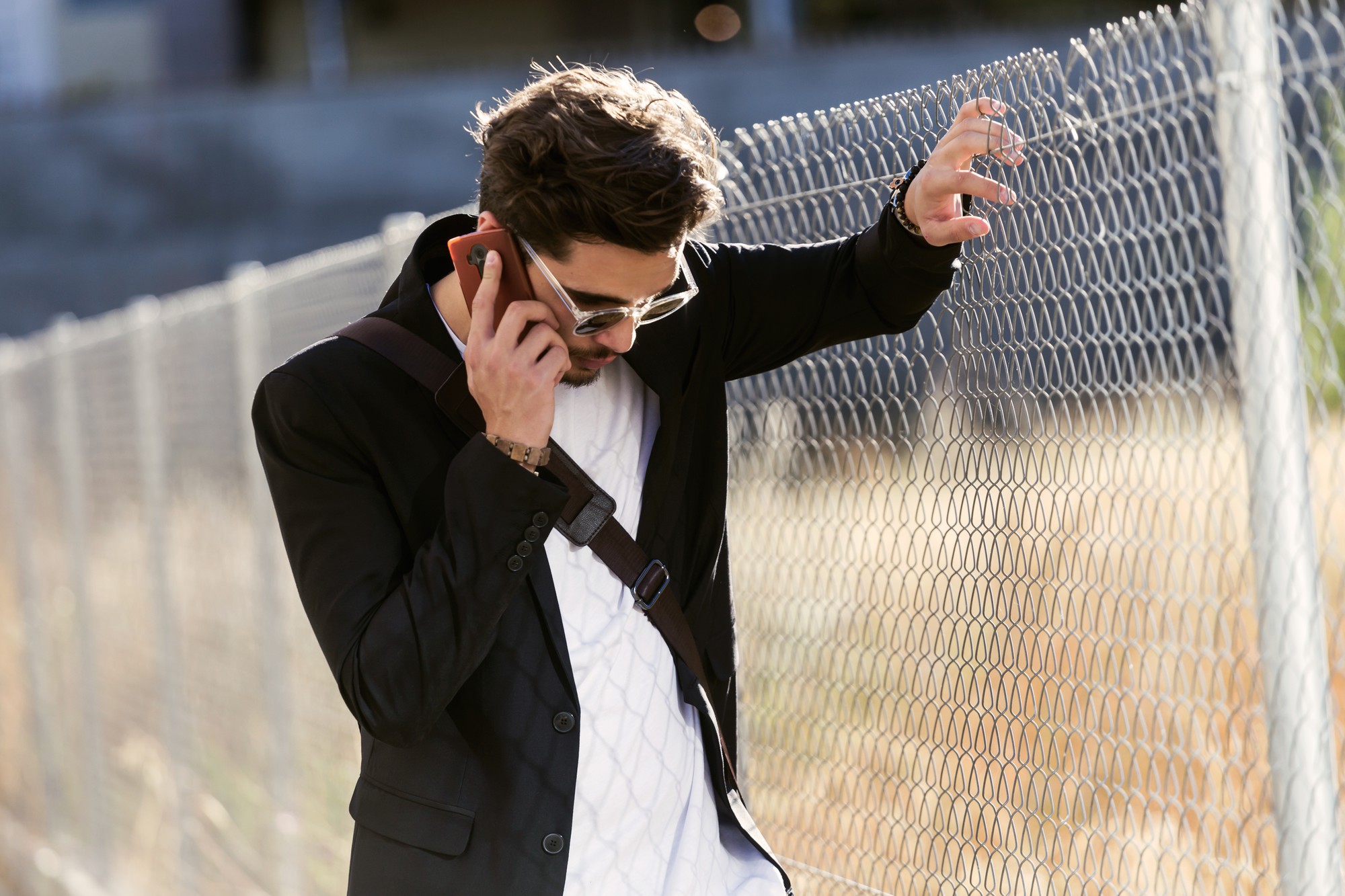Retrato de jovem bonito usando seu telefone celular na rua.