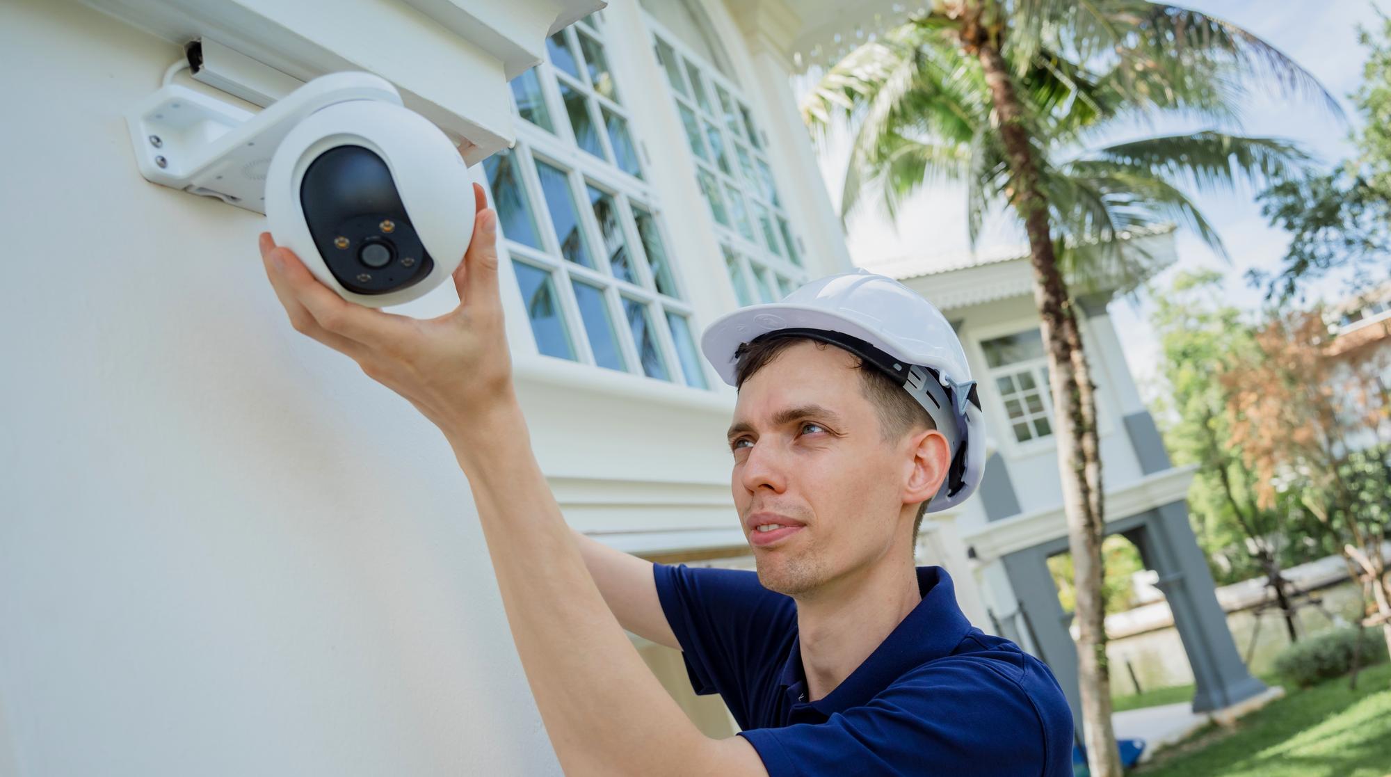 Um técnico instala uma câmera de CCTV na fachada de um edifício residencial