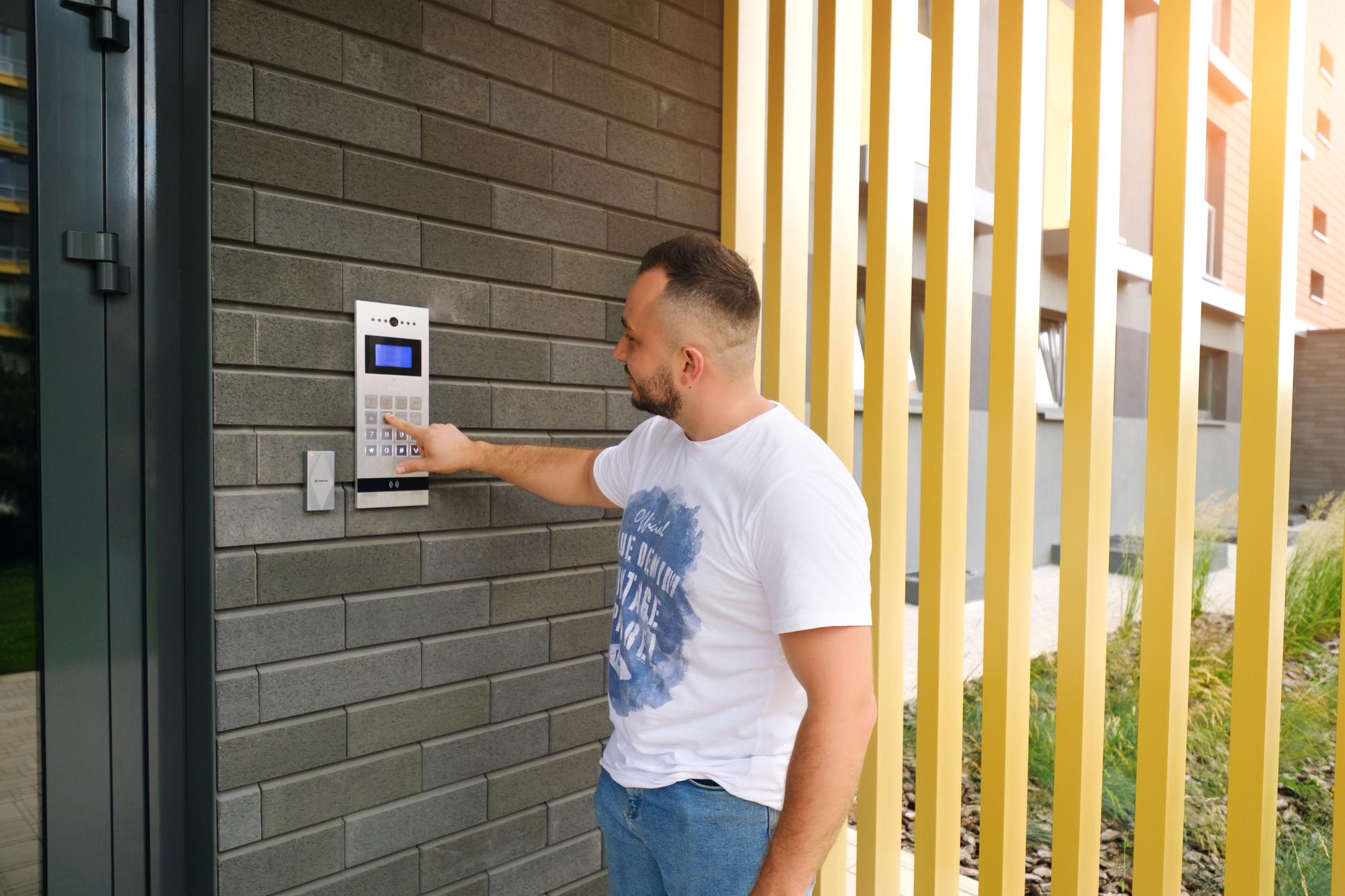 Homem fica no prédio de um prédio residencial e disca o código da porta do interfone