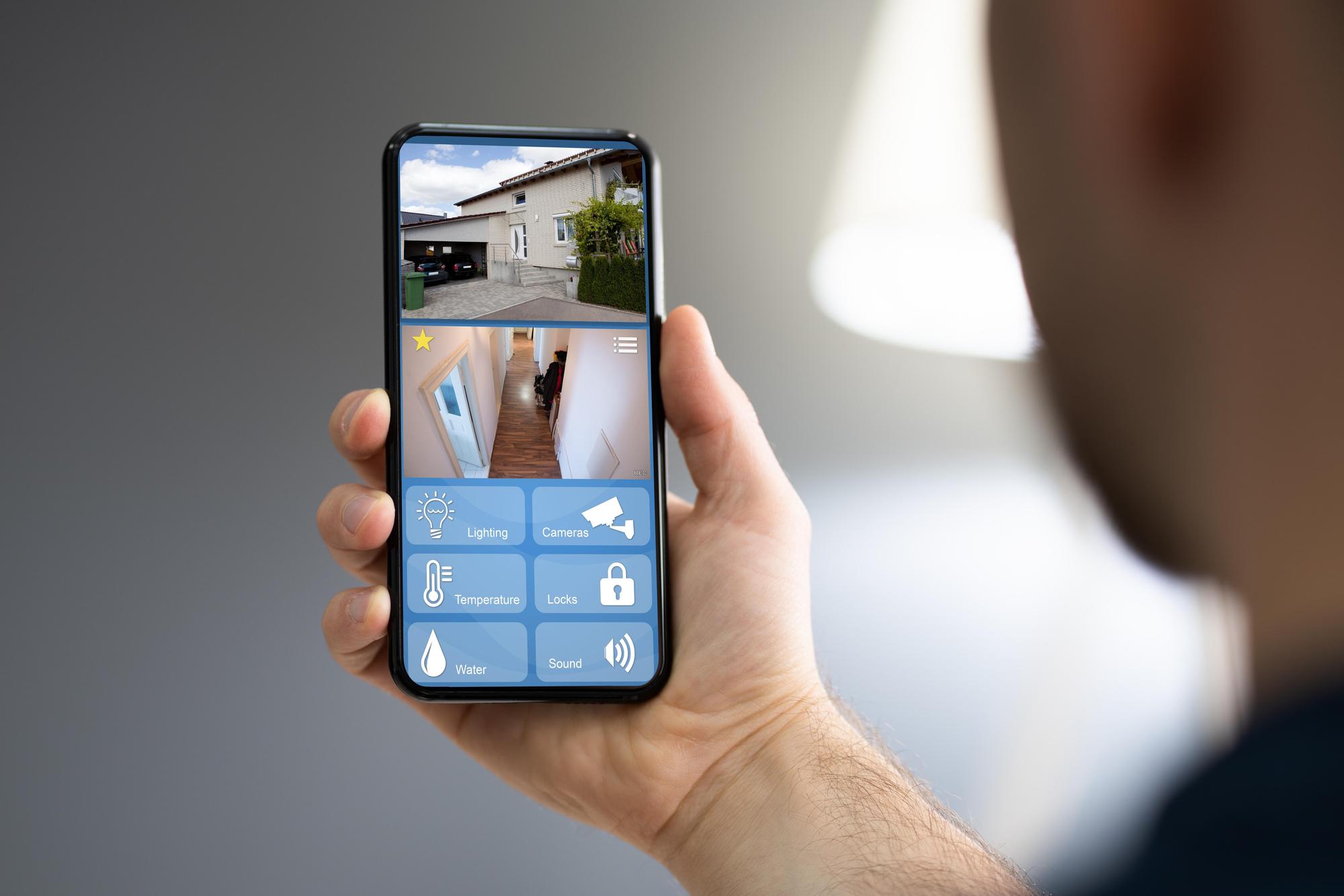 Pai de família visualizando imagens das câmeras de segurança no smartphone enquanto relaxa na sala de estar