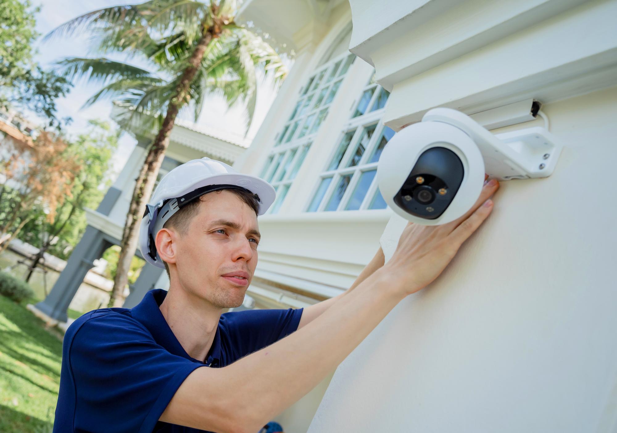 Um técnico instala uma câmera de CCTV na fachada de um edifício residencial