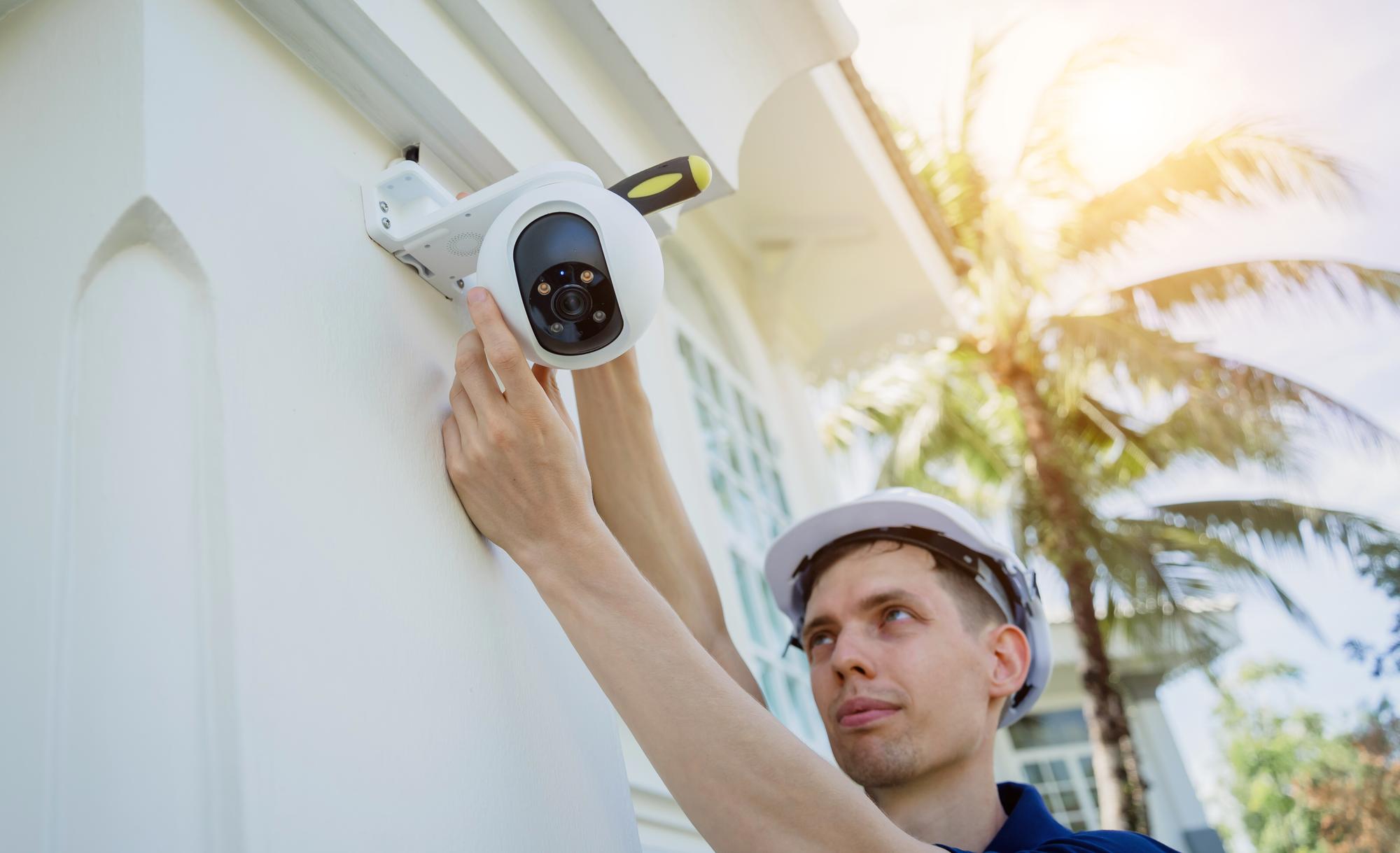 Um técnico instala uma câmera de CCTV na fachada de um edifício residencial