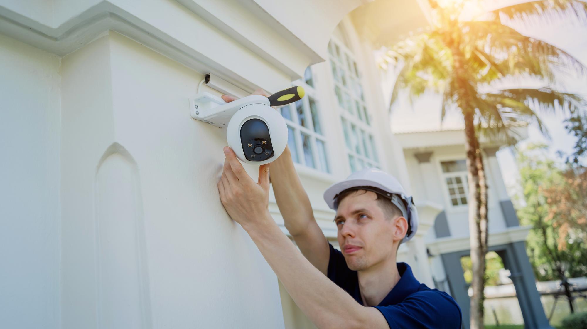 Um técnico instala uma câmera de CCTV na fachada de um edifício residencial