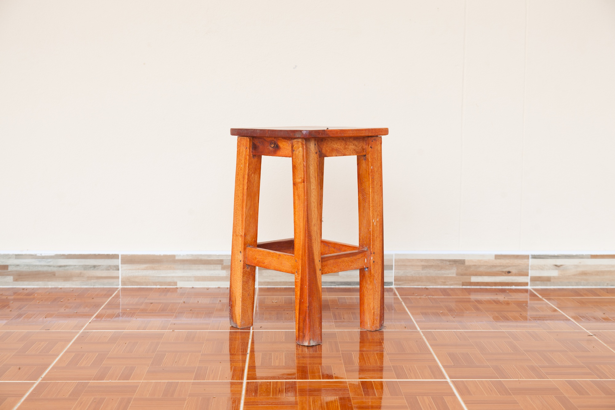 Banqueta cepo de madeira maciça da Arwo posicionada em uma sala de estar de luxo ao lado de um sofá de linho cinza