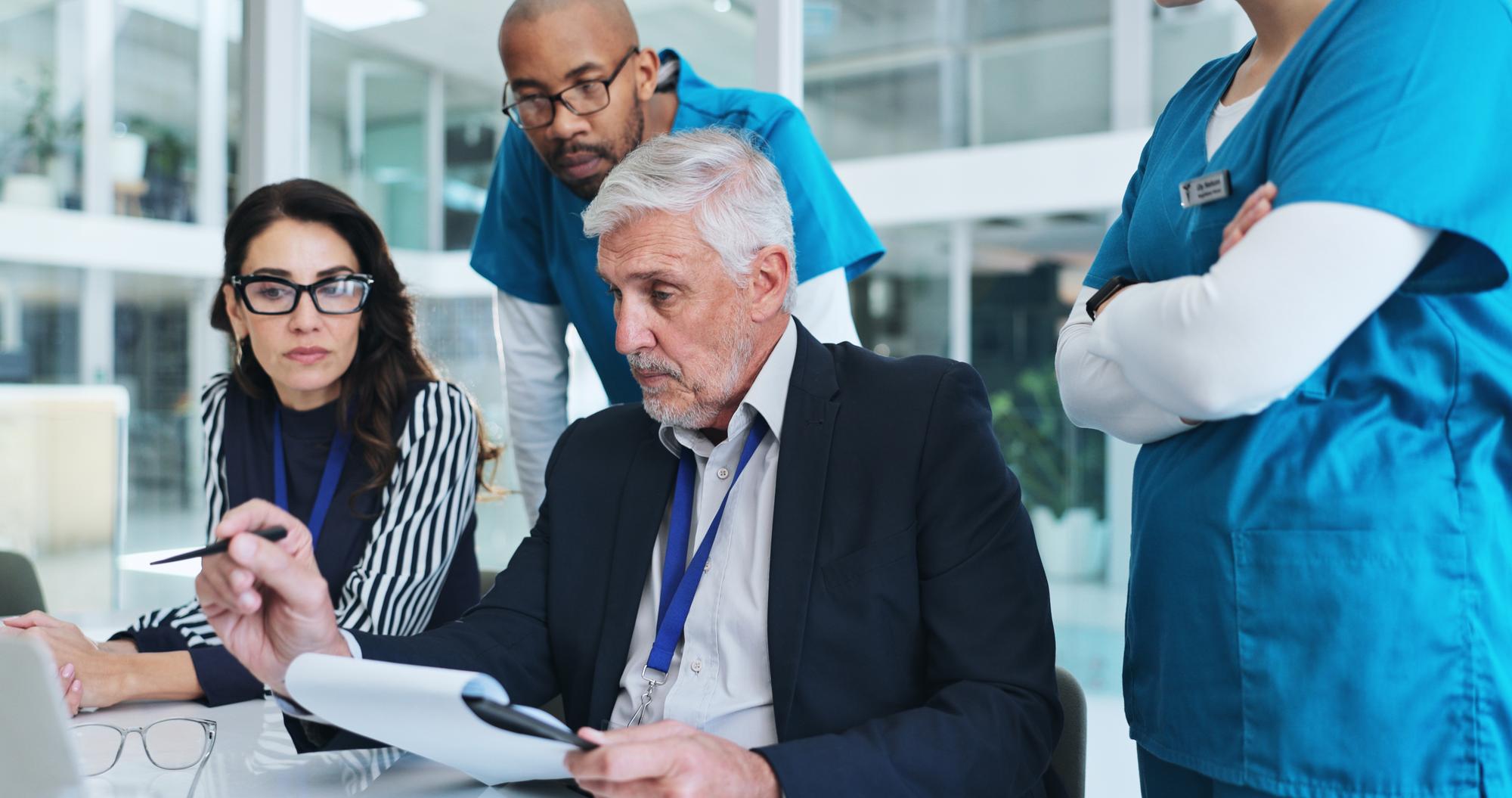 Pessoal da equipa médica e reunião na sala de reuniões no portátil para relatar resultados e feedback sobre o projecto de cuidados de saúde Trabalho em conjunto do hospital e funcionários em discussão para planeamento ou estratégia de brainstorming