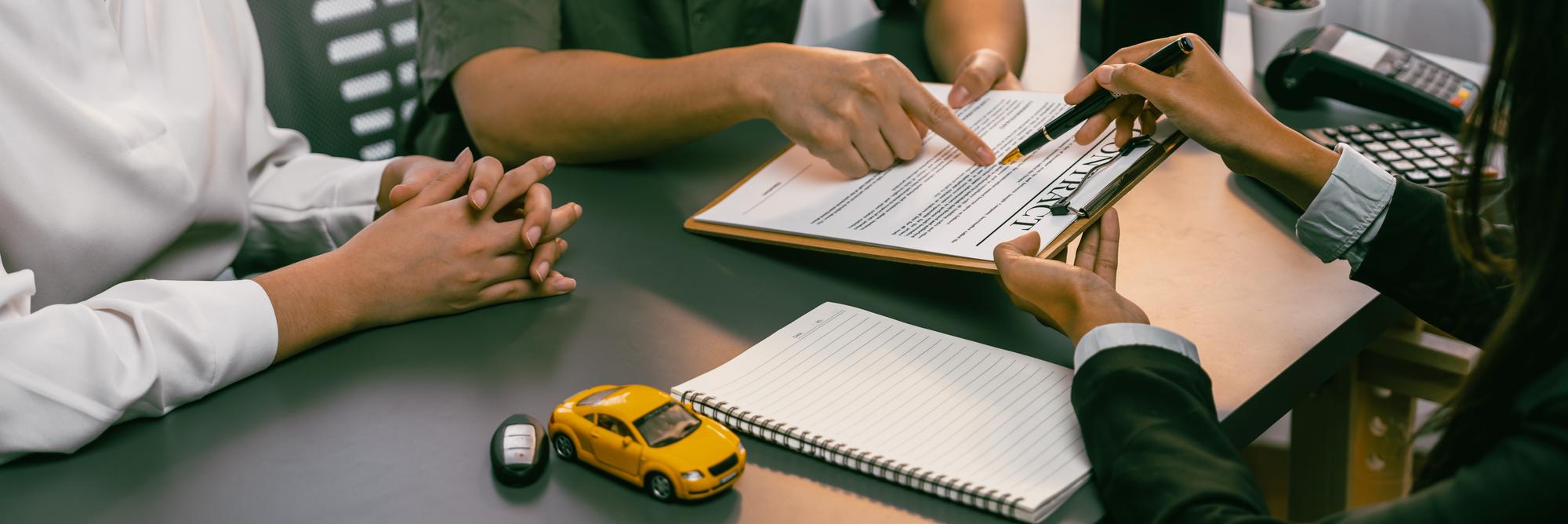O concessionário de automóveis calcula a taxa de juro e os custos do empréstimo de automóvel, oferecendo serviços financeiros e de seguros, enquanto o cliente lê os termos e o acordo do contrato no escritório da concessionária Prodigy