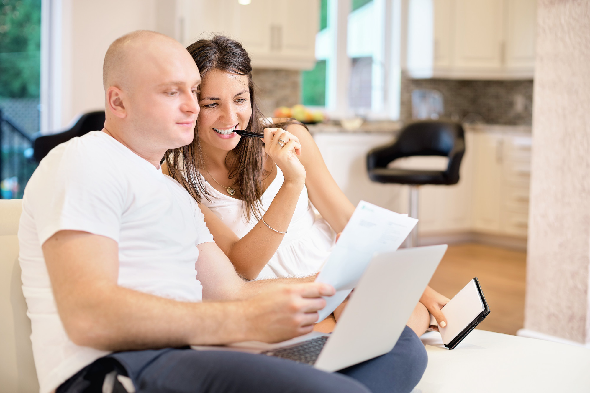 Jovem casal no sofá com o laptop e conta a conta para pagamento. O conceito de serviços públicos, dívida, pessoas e crédito.