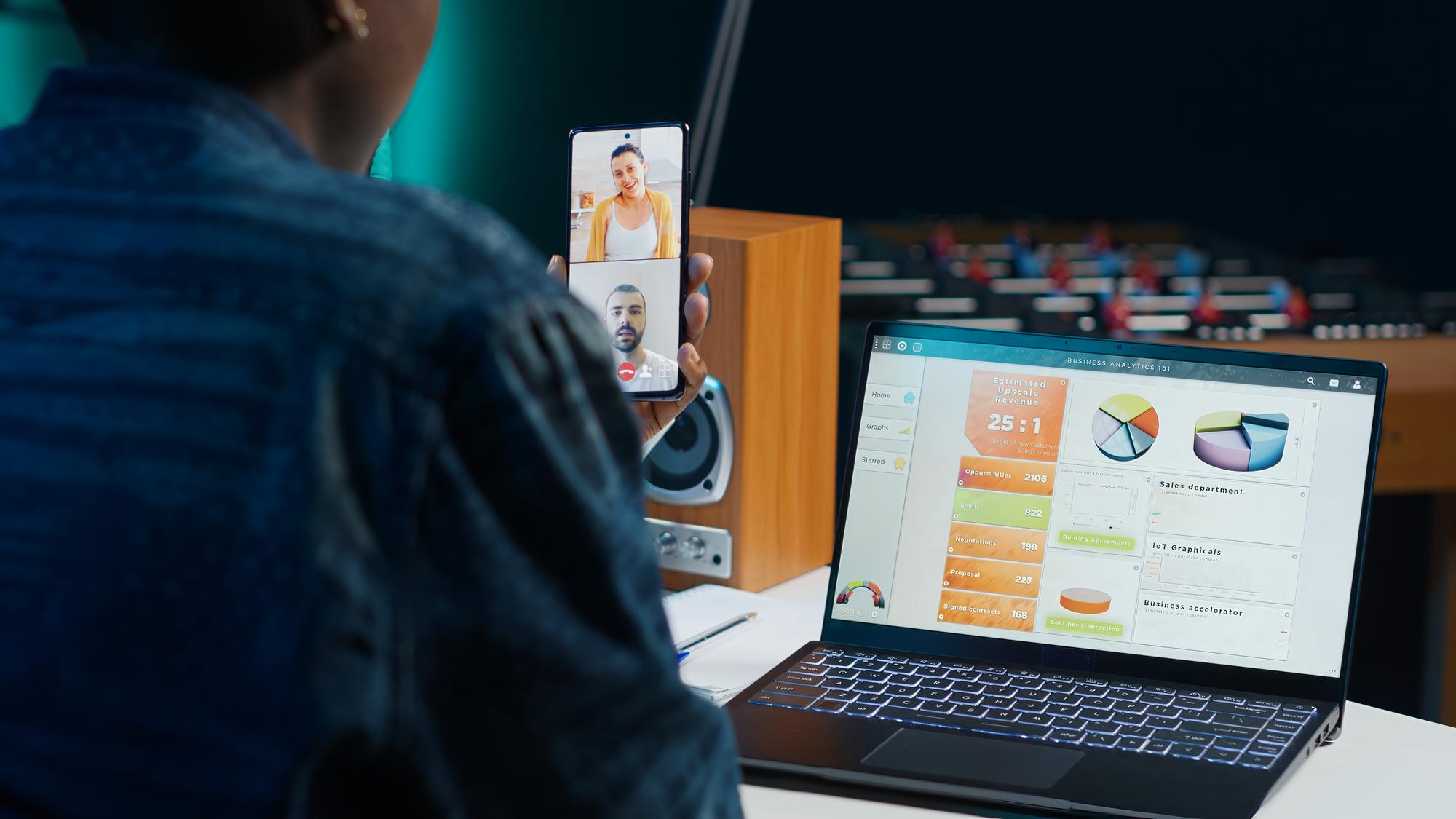 Trabalhador remoto em videoconferência telefônica on-line com colegas analisando pesquisas