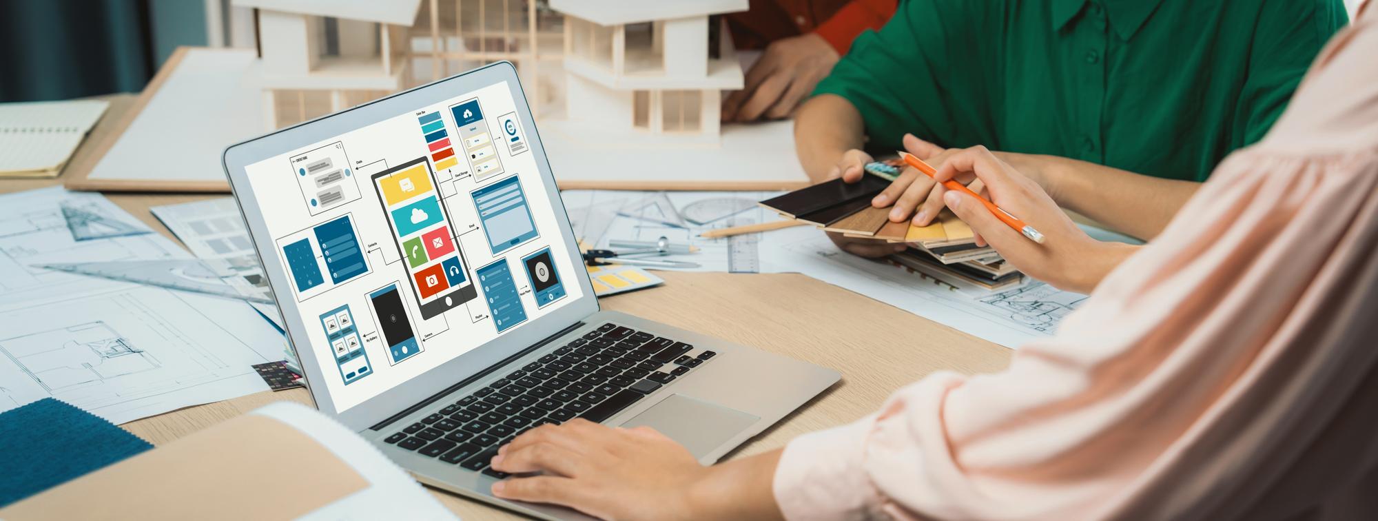 A imagem recortada da equipe de designer de interiores apresenta cores usando amostras de cores enquanto o laptop exibia designs de UI e UX para aplicativos e sites para dispositivos móveis Design criativo e conceito de negócios Variegado