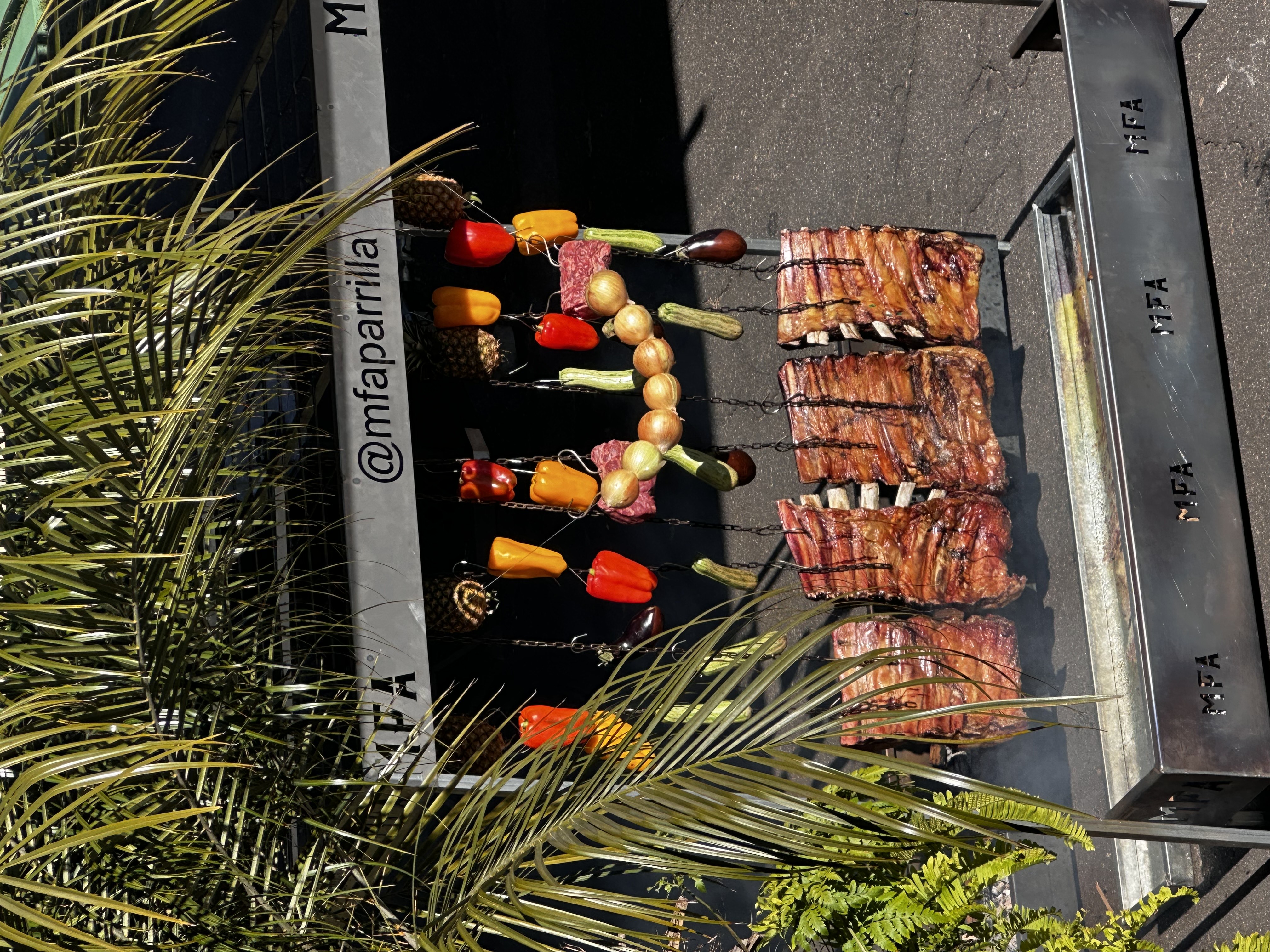 Equipe de buffet profissional servindo picanha grelhada em um ambiente corporativo elegante com decoração em tons de roxo e cinza.