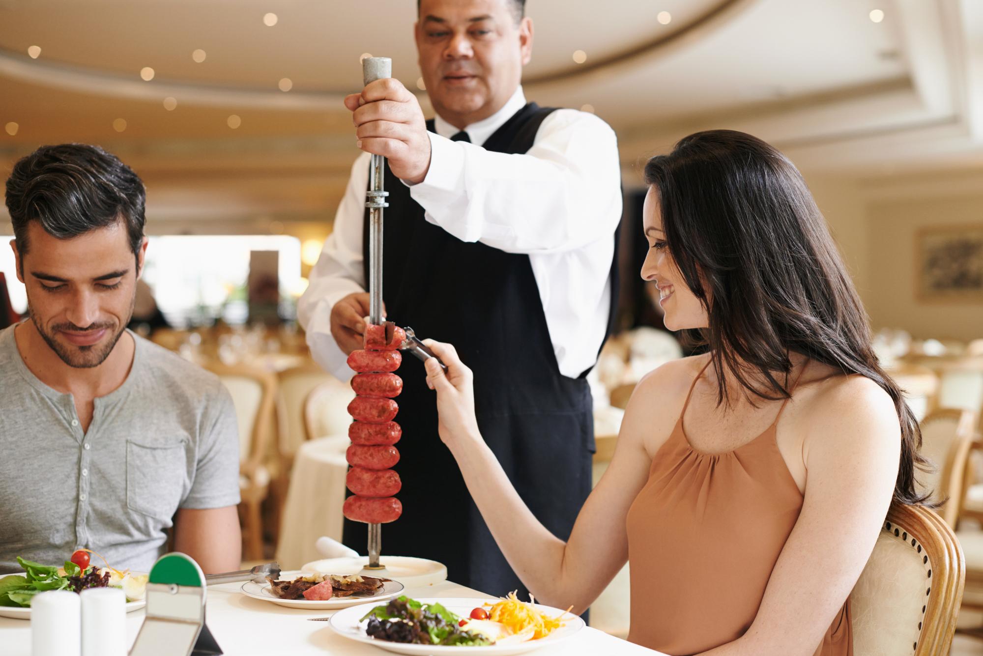 Casal jantar fino e garçom servindo comida ou kebab de salsicha em espeto ou restaurante aniversário ou nutrição homem mulher e relacionamento datas de ligação na Itália com água esculpir refeição ou comer