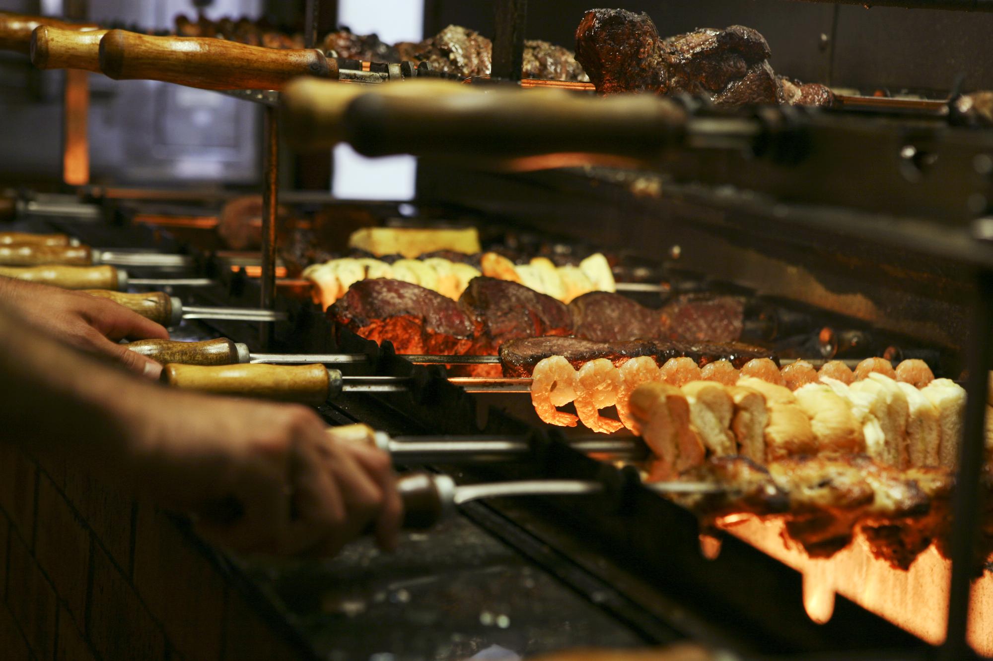 Mãos cortadas fazendo comida em uma grelha de churrasco