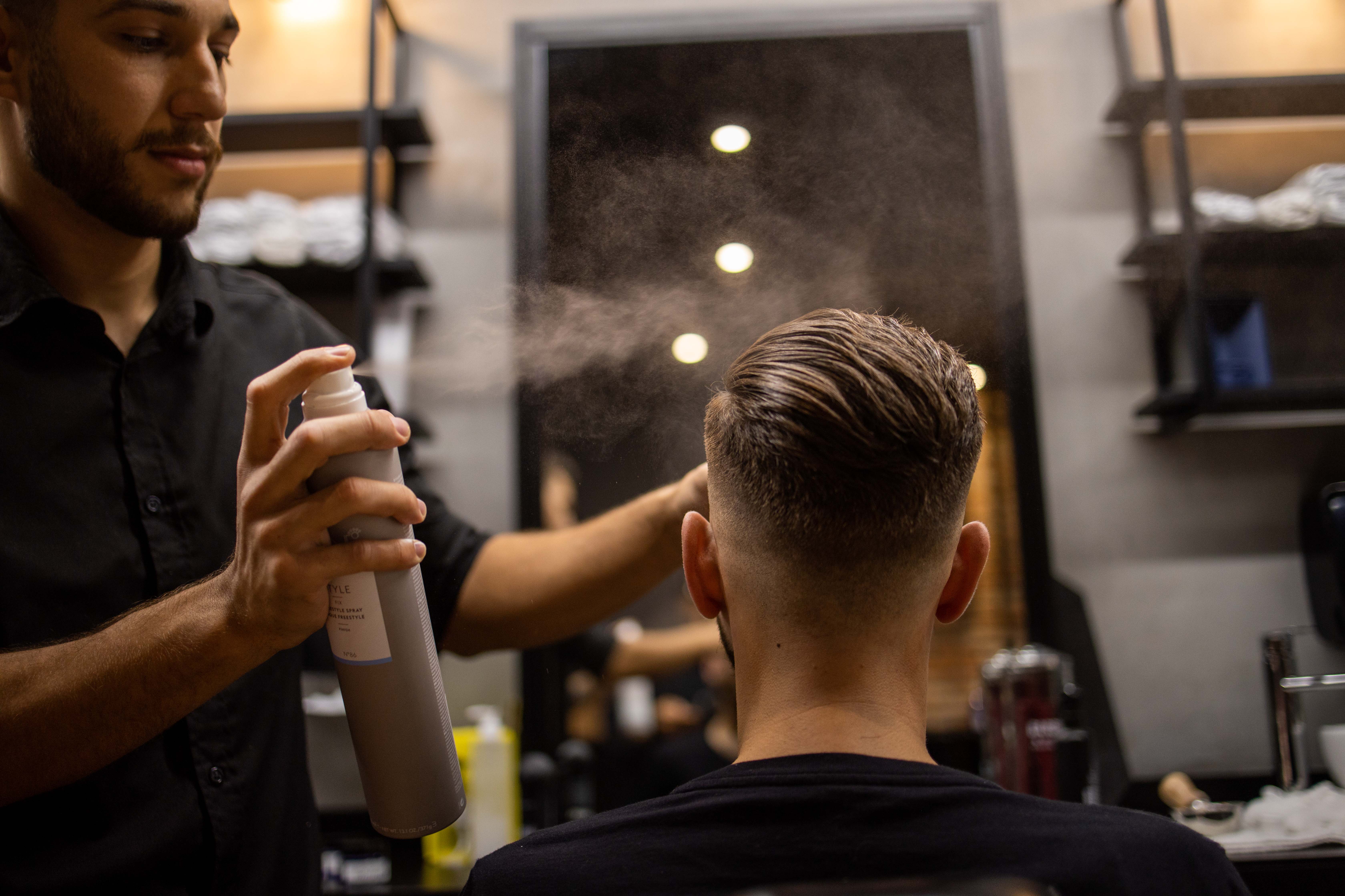 Interior de barbearia luxuosa com poltronas de couro, iluminação quente e foco em produtos de alta gama como Keune 1922