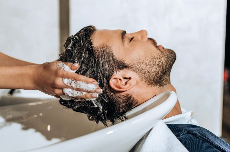 Executivo elegante em ambiente de escritório premium observando seu reflexo com foco no cabelo impecável