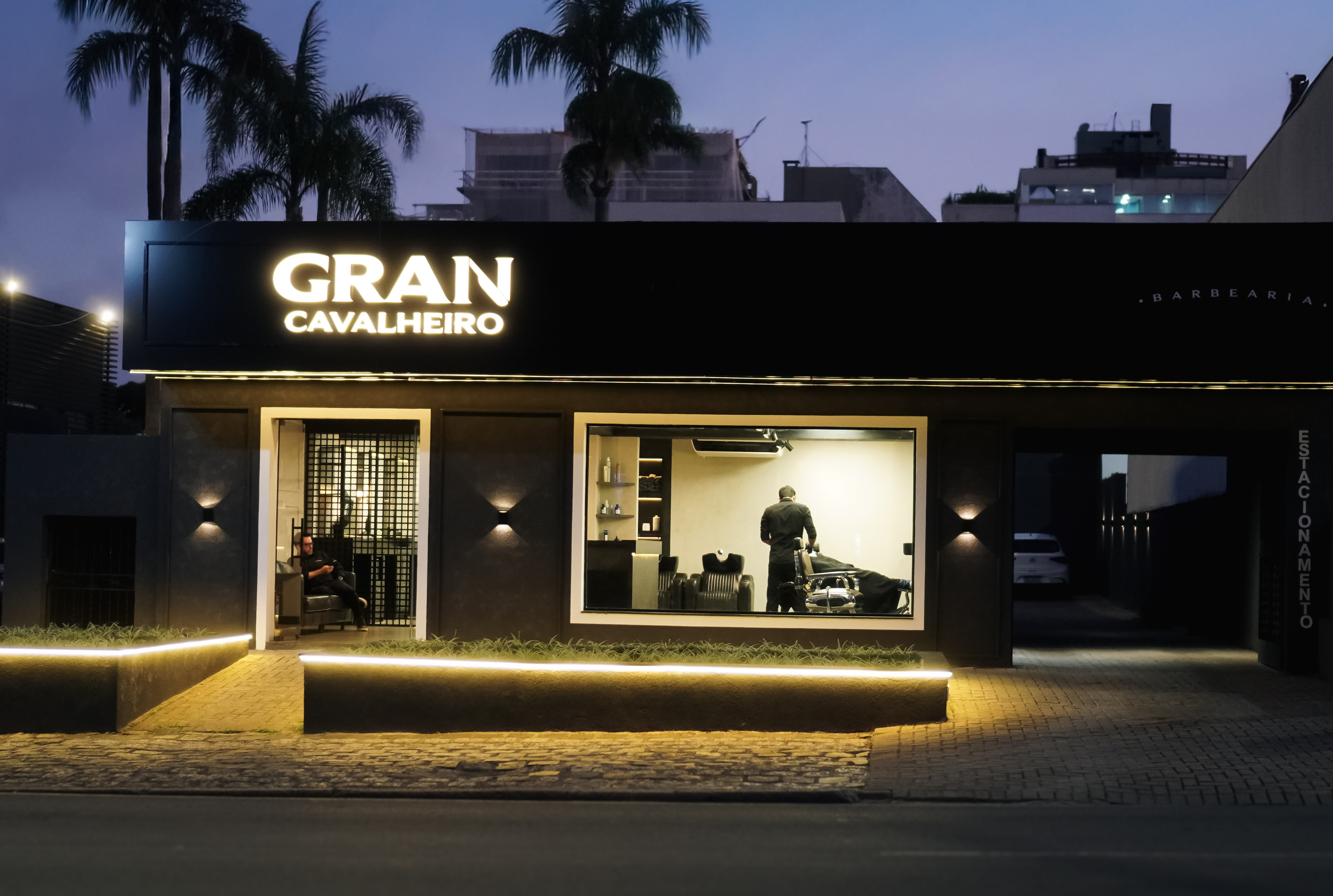 Ambiente sofisticado de uma barbearia premium no Batel com poltronas de couro e tons de azul e prata