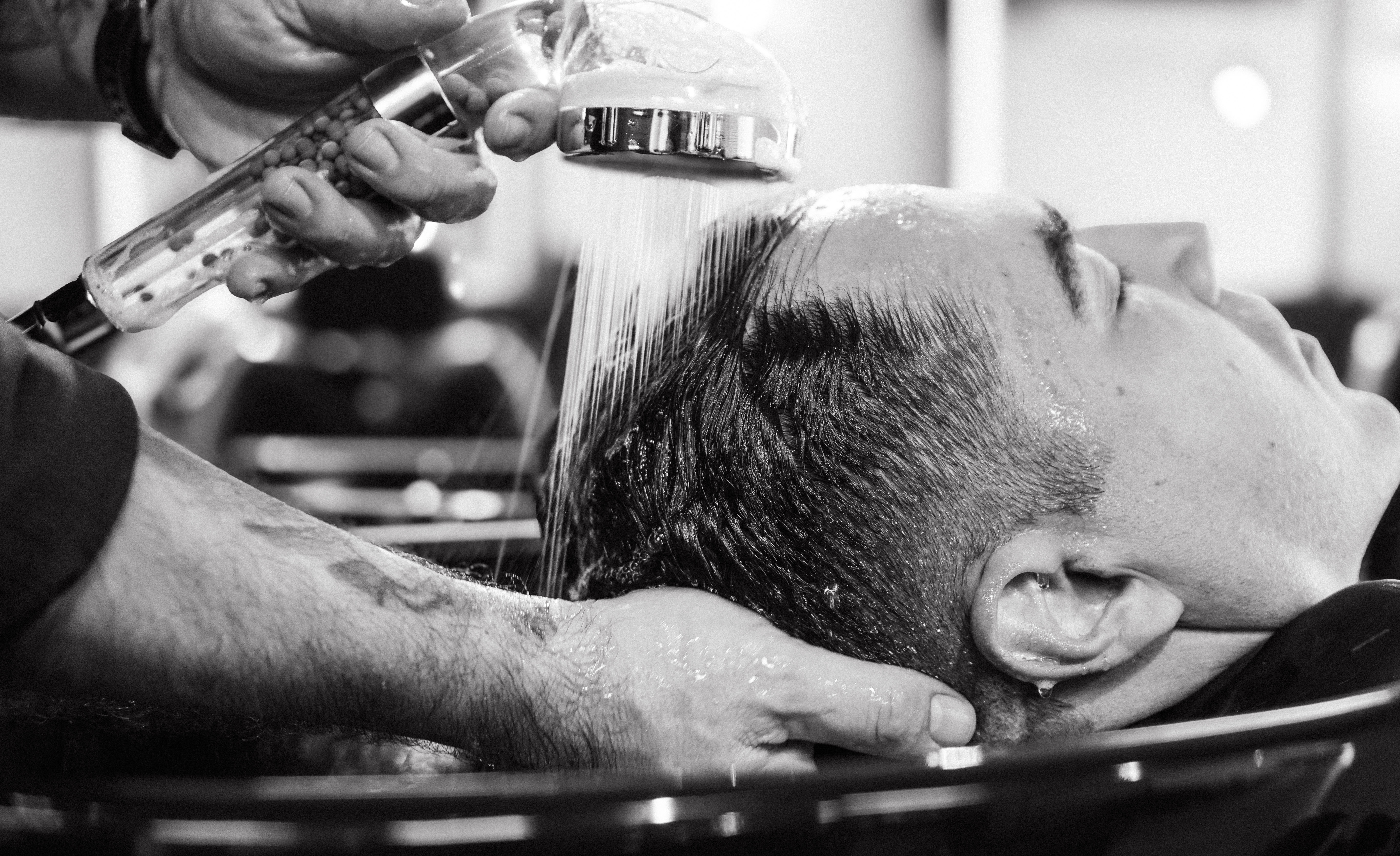 Detalhe de produtos Keune sendo aplicados em barba masculina em um ambiente sofisticado com iluminação acolhedora