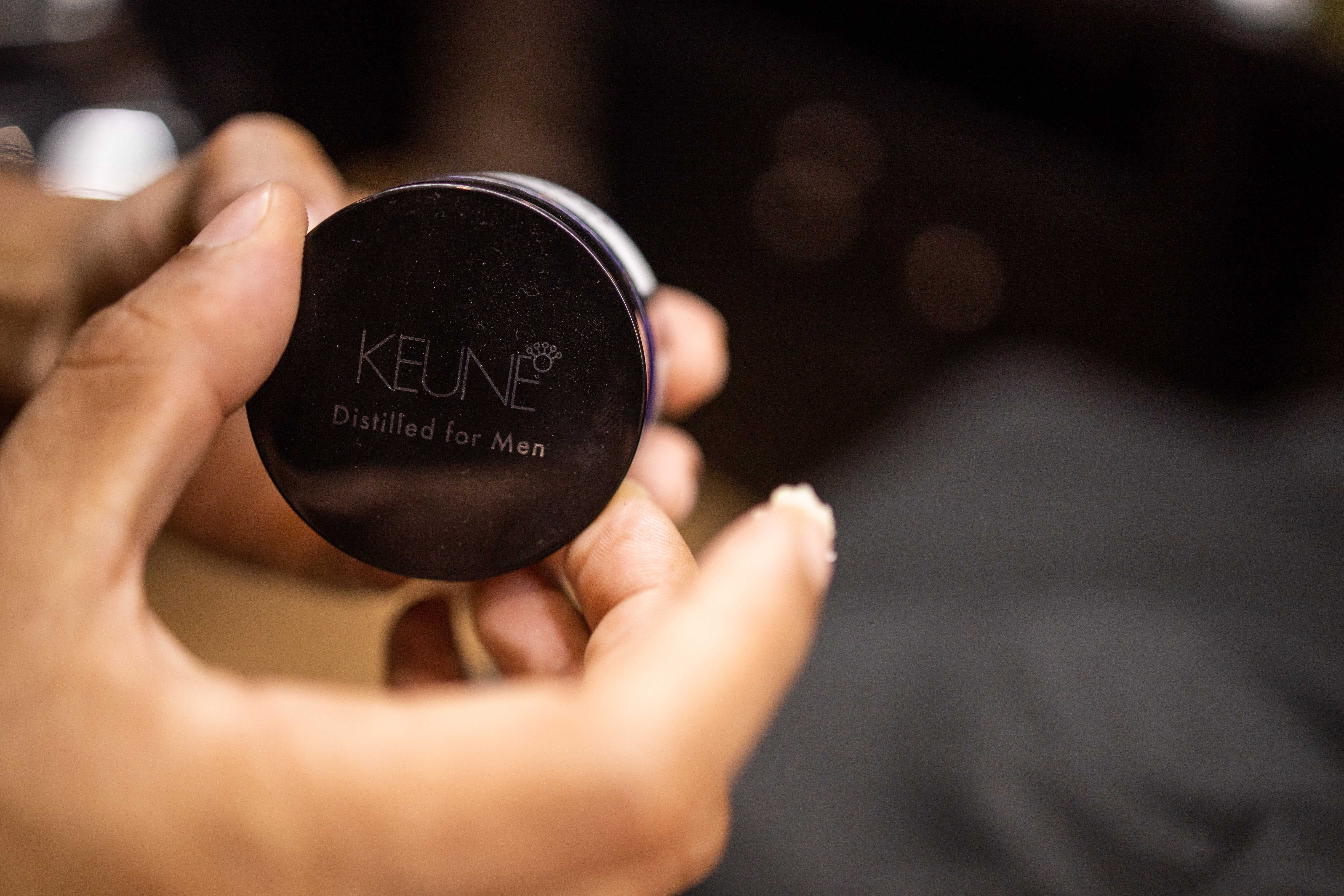 Detalhe de produtos Keune e ferramentas de barbearia de luxo em bancada organizada
