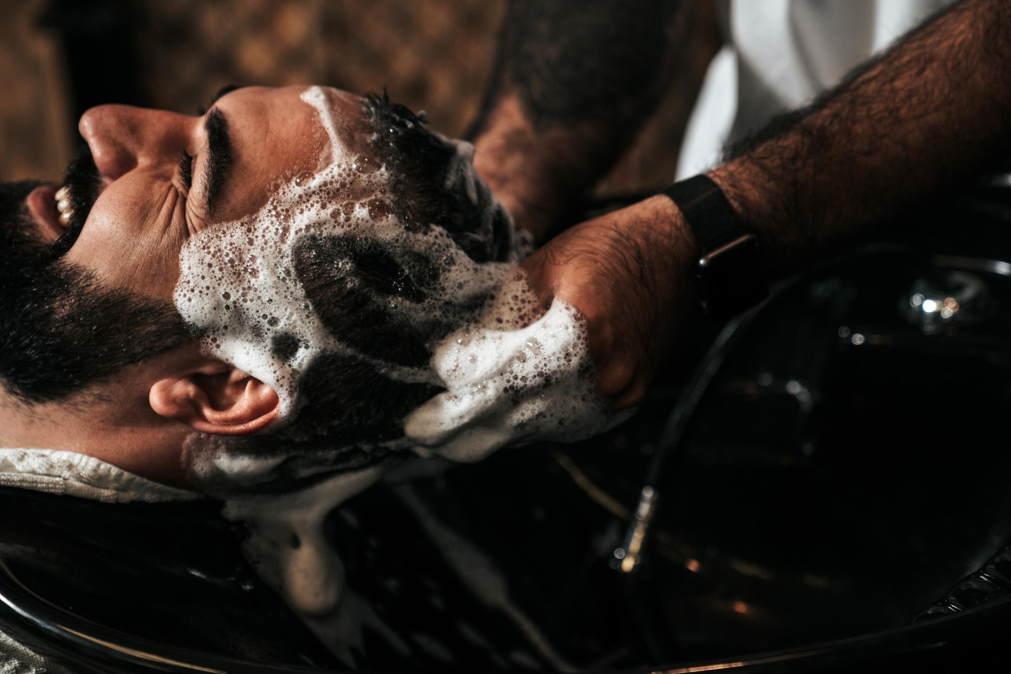 Cabeleireiro atendendo um cliente em uma barbearia