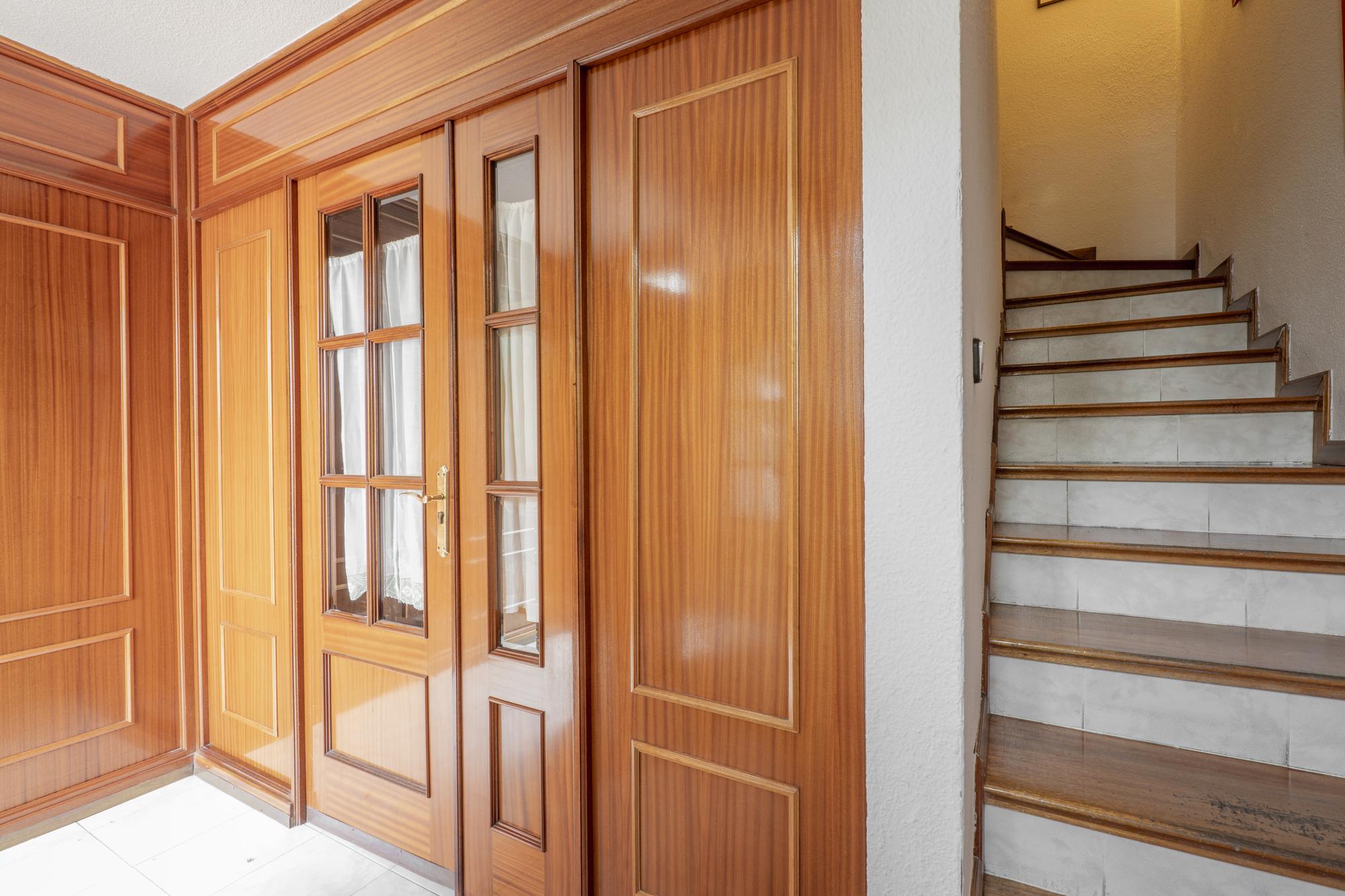 Escadas de uma moradia isolada com degraus em mármore de cor creme e uma despensa com frigorífico e garrafeira