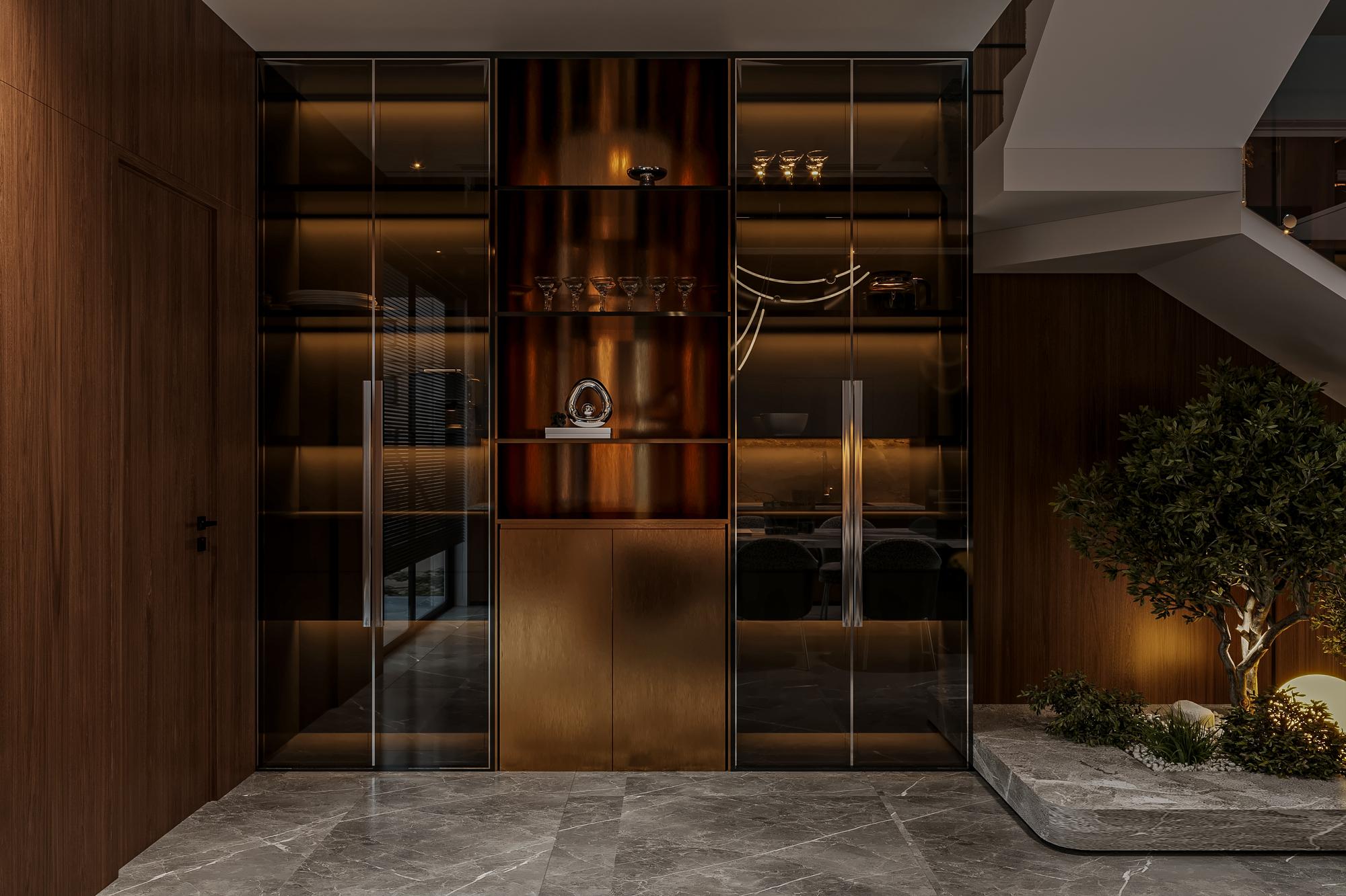 O interior da casa duplex moderna apresenta uma entrada com armários de madeira escura, portas de vidro e um chão de pedra