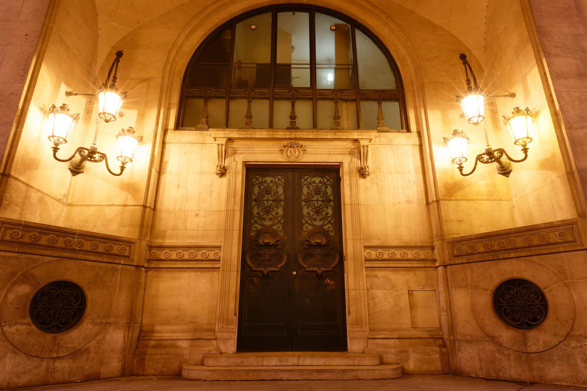 Porta laqueada branca em corredor de luxo com iluminação suave e molduras clássicas nas paredes