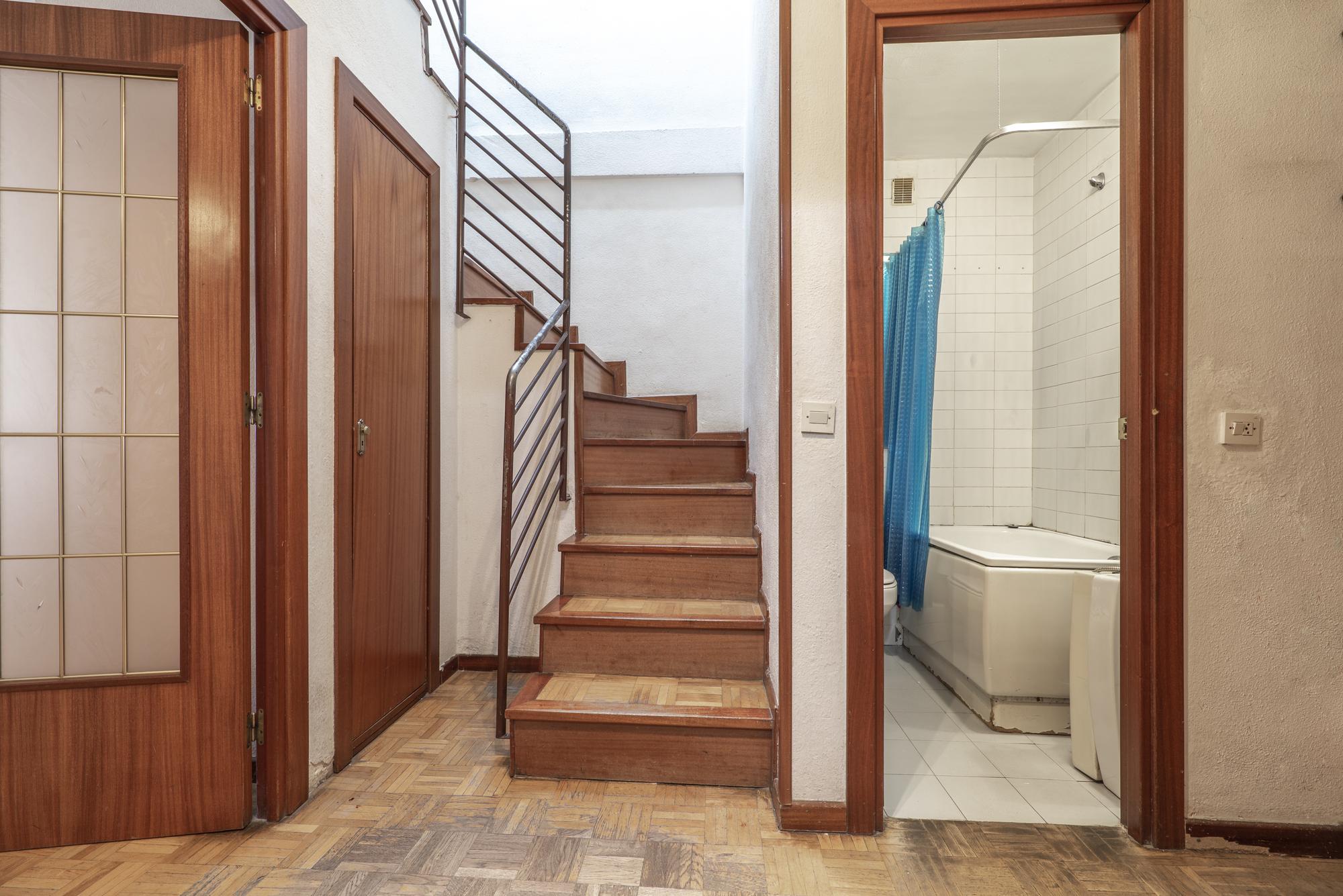 Distribuidor de uma casa residencial com escadas e corrimão de metal e piso em parquet de carvalho