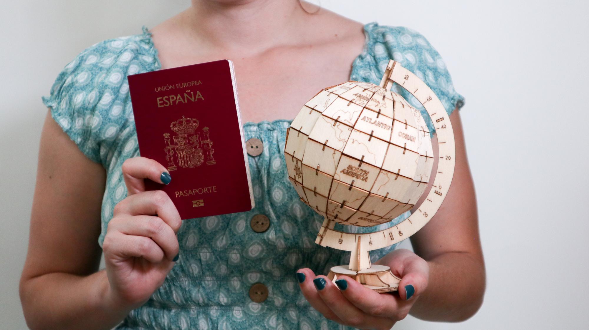 Menina com um passaporte espanhol e um mapa de madeira do mundo Vagas de viagem