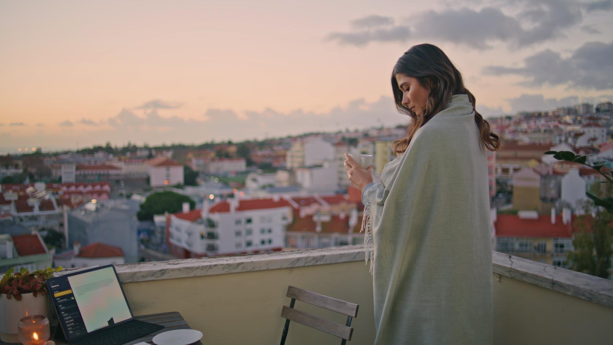 Menina relaxada olhando para a paisagem da cidade no pôr-do-sol em terraço em closeup mulher fazendo foto