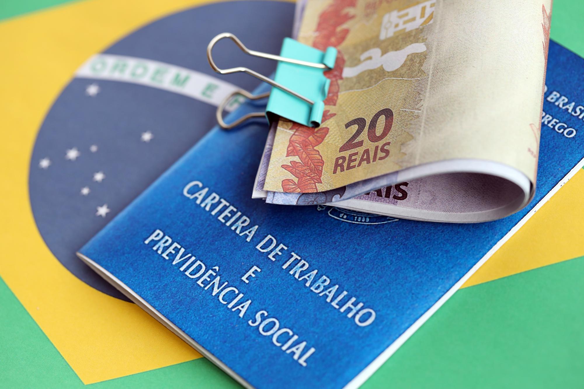 Cartão de trabalho brasileiro e livro azul da segurança social e notas de dinheiro em reais com bandeira federativa