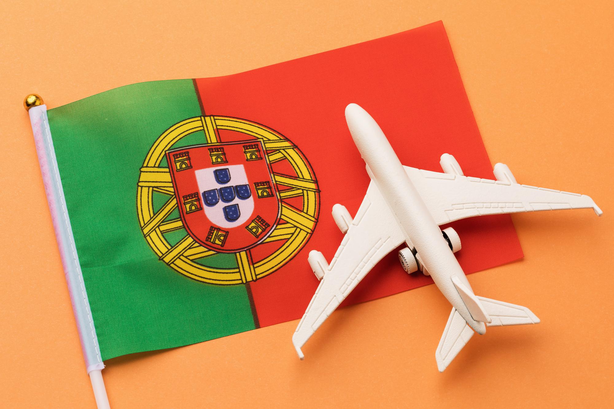 Bandeira portuguesa e avião de brinquedo sobre fundo colorido, conceito sobre o tema da viagem a Portugal