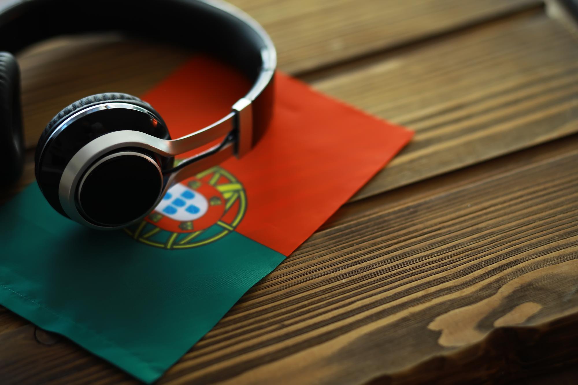 Fones de Ouvido sobre a Bandeira Portuguesa em Mesa de Madeira Representando Música e Cultura