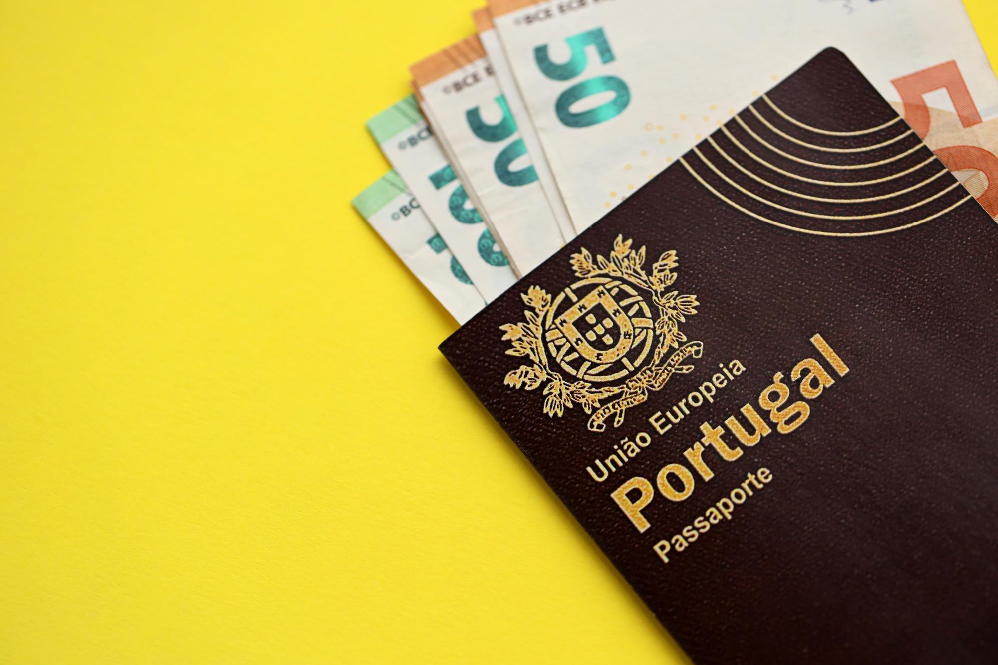 Passaporte português vermelho da União Europeia e dinheiro em fundo amarelo de perto