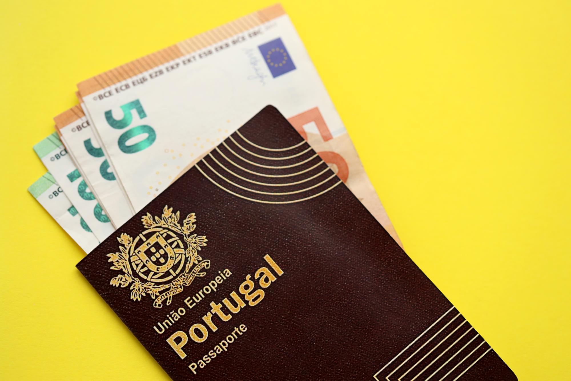Passaporte português vermelho da União Europeia e dinheiro em fundo amarelo de perto