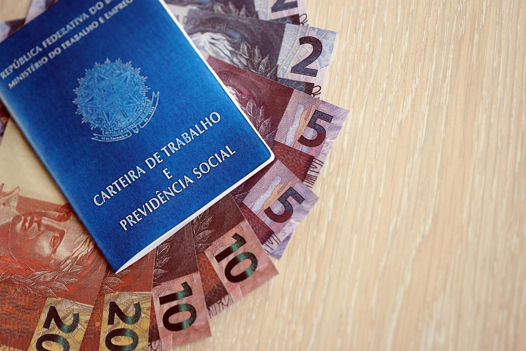 Cartão de trabalho brasileiro e livro azul da segurança social e notas de dinheiro em reais