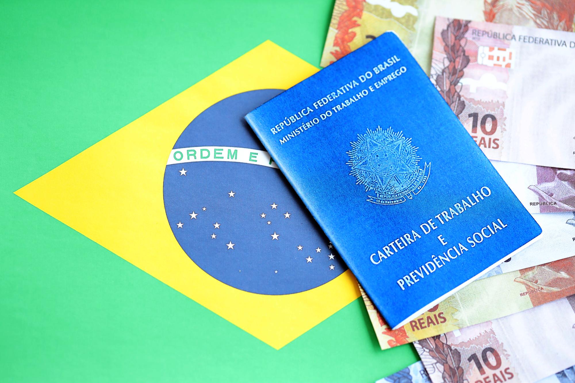 Cartão de trabalho brasileiro e livro azul da segurança social e notas de dinheiro em reais com bandeira federativa