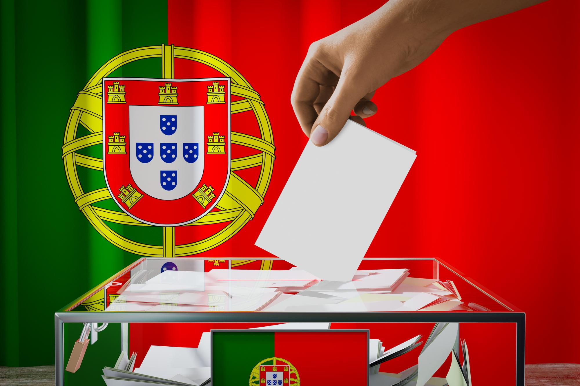 Mão de bandeira de Portugal deixando cair o cartão de voto em um conceito de eleição de votação de caixa