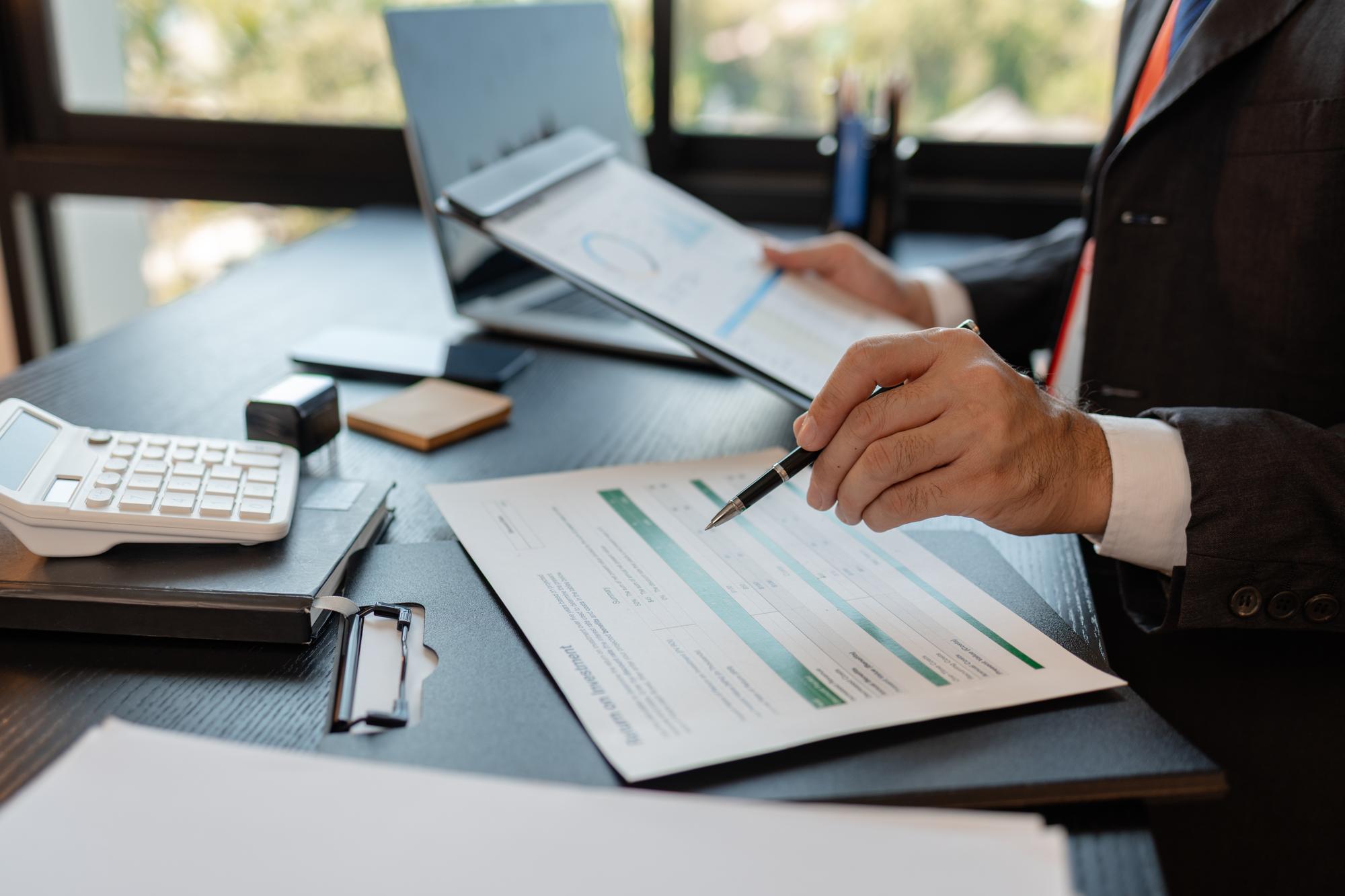 Um empresário está revisando documentos de contabilidade e estatísticas financeiras em seu escritório particular. O estatístico prepara vários gráficos e documentos para uma reunião.