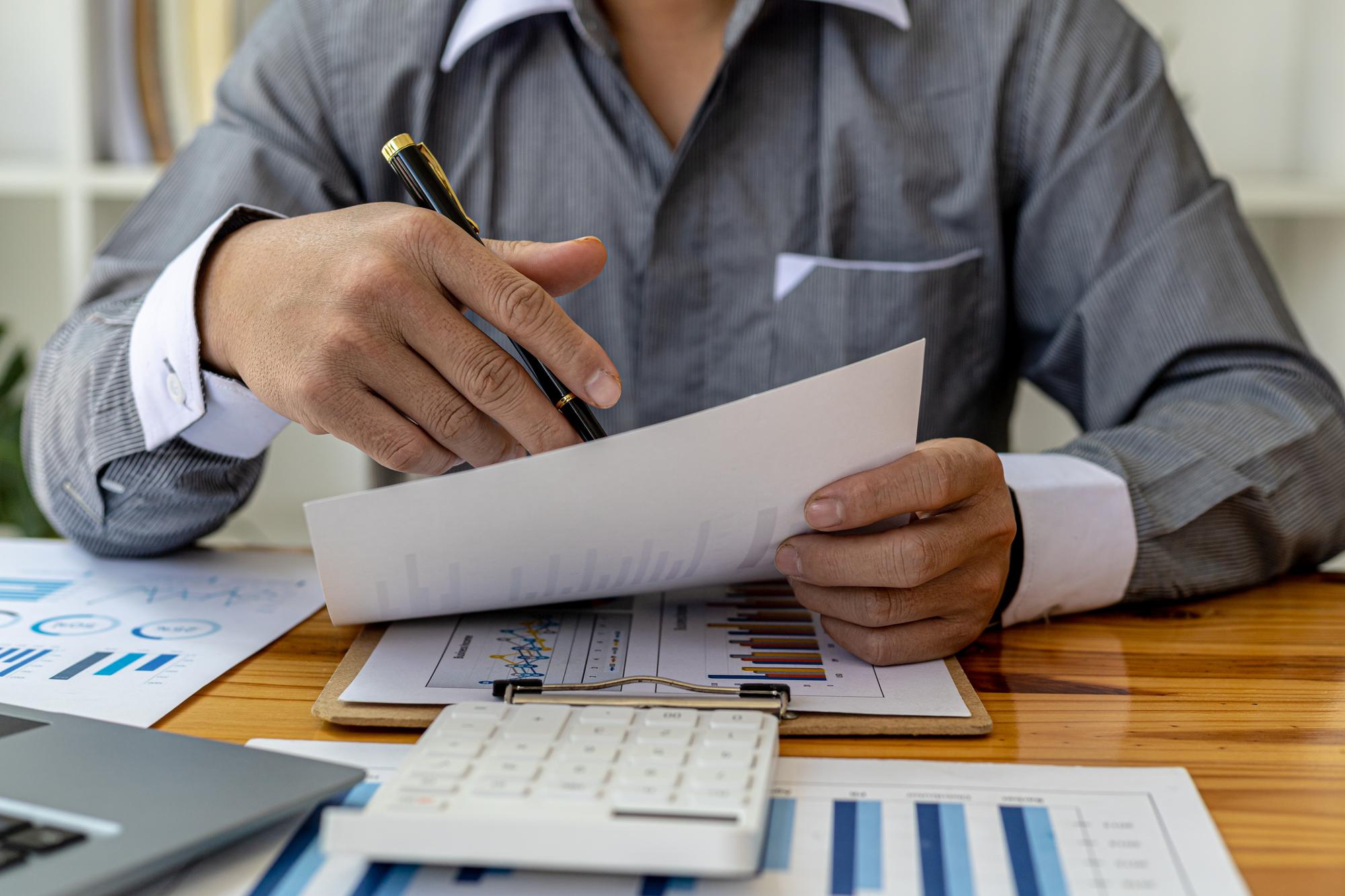 Homens de negócios estão olhando os documentos financeiros da empresa para analisar problemas e encontrar soluções antes de levar as informações para uma reunião com um sócio. Conceito financeiro.