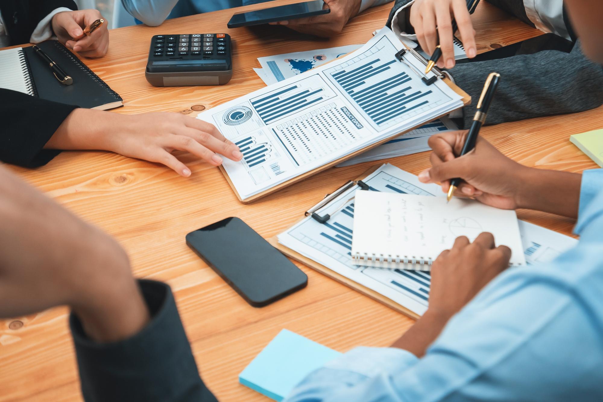 Equipe multirracial de analistas usa dados do painel de BI para analisar relatórios financeiros na mesa de reuniões Grupo de diversos empresários utiliza análise de dados da FIntech para decisões de marketing empresarial Concord