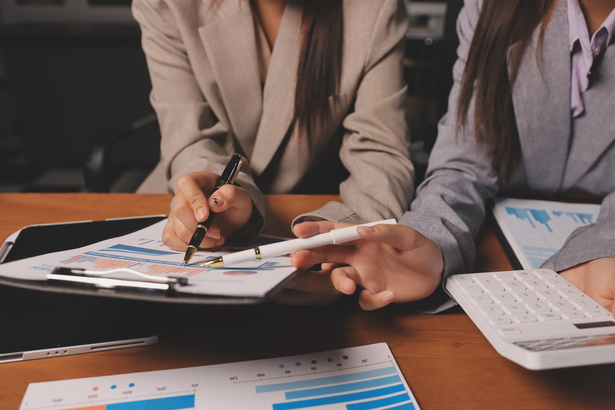 Grupo de empresários confiantes apontam para gráficos e gráficos para analisar dados de mercado balanço da conta lucro líquido para planejar novas estratégias de vendas para aumentar a capacidade de produção