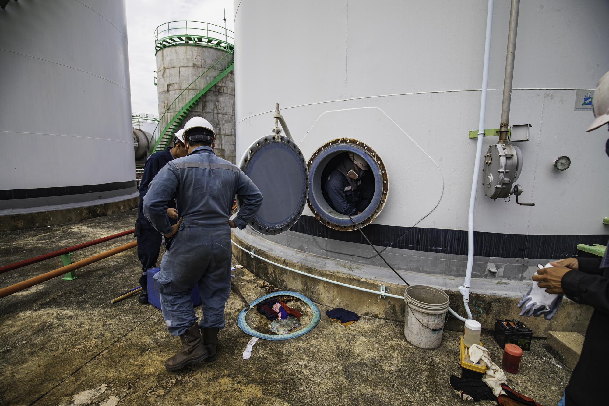 Trabalhador do sexo masculino no espaço confinado da área de interface do óleo químico de carbono do tanque