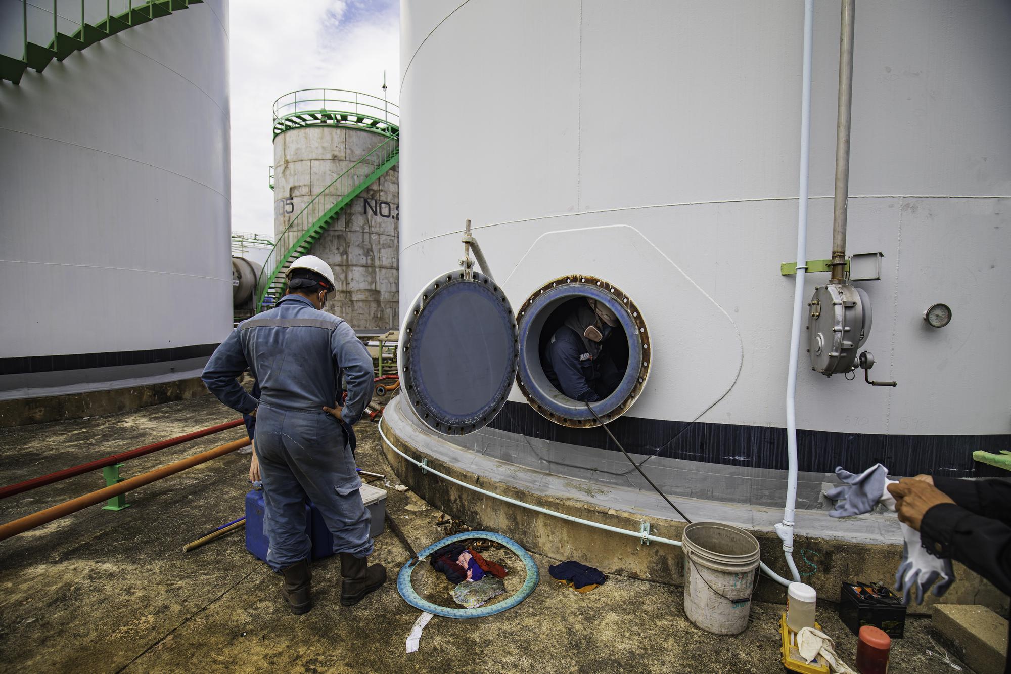 Trabalhador do sexo masculino no espaço confinado da área de interface do óleo químico de carbono do tanque