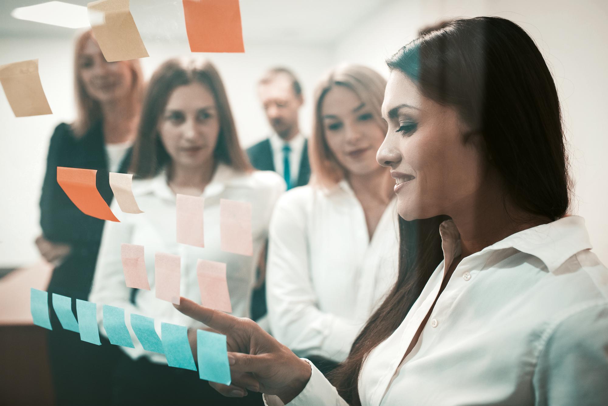 Equipe amigável de empresários fazendo brainstorming juntos olhando adesivos coloridos na porta do escritório ..
