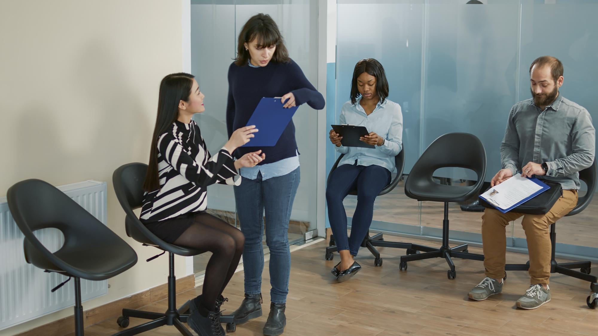 Empregada grávida levando mulher asiática no escritório de reunião para participar de entrevista de emprego com trabalhador de RH. Candidato com oportunidade de carreira sentado na sala de espera antes da nomeação do recrutamento.