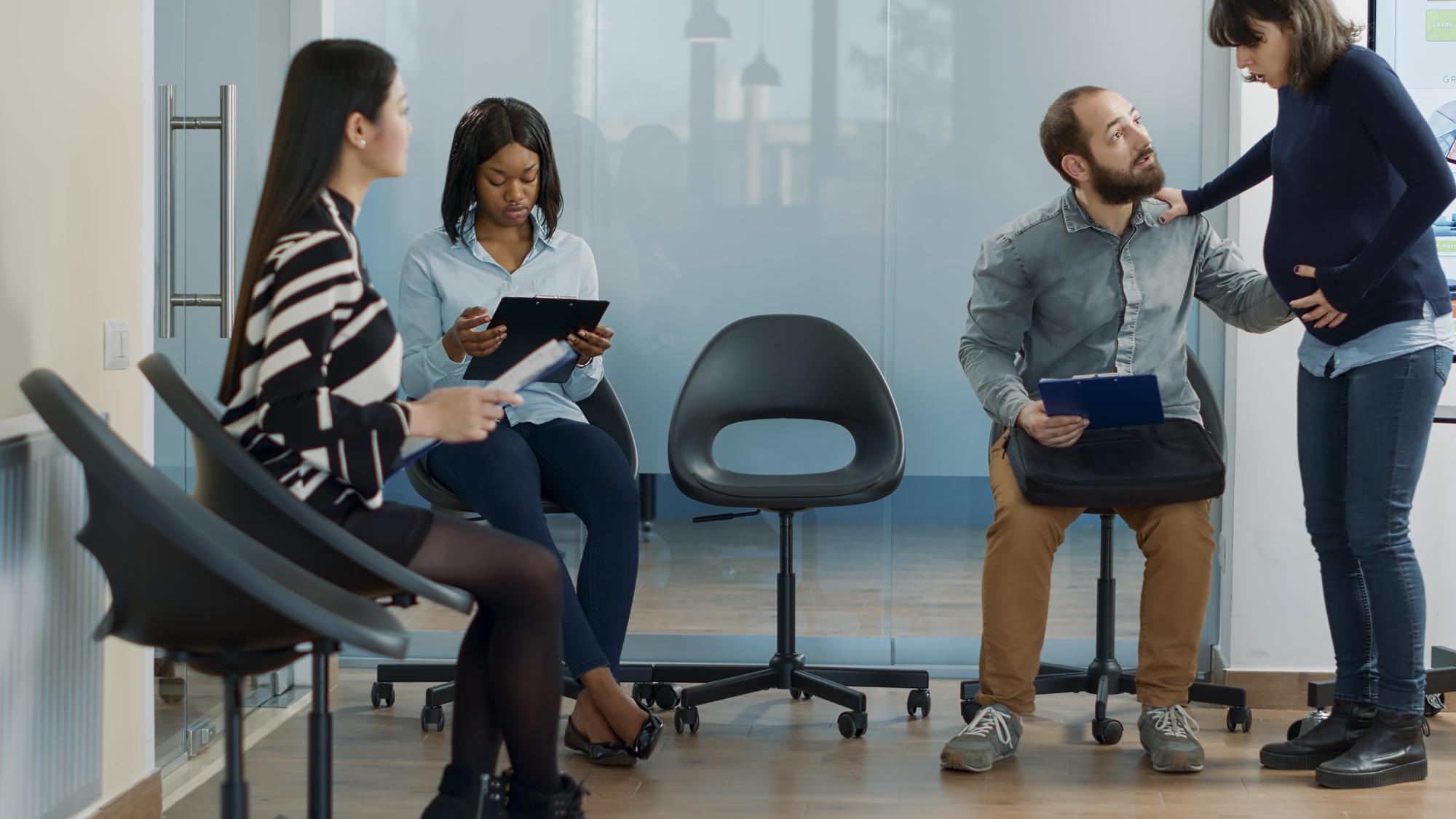 Candidato masculino participando de entrevista de emprego com funcionária grávida, preparando-se para reunião de recrutamento profissional no escritório. Mulher convidando o homem para iniciar a nomeação de candidatura de emprego.
