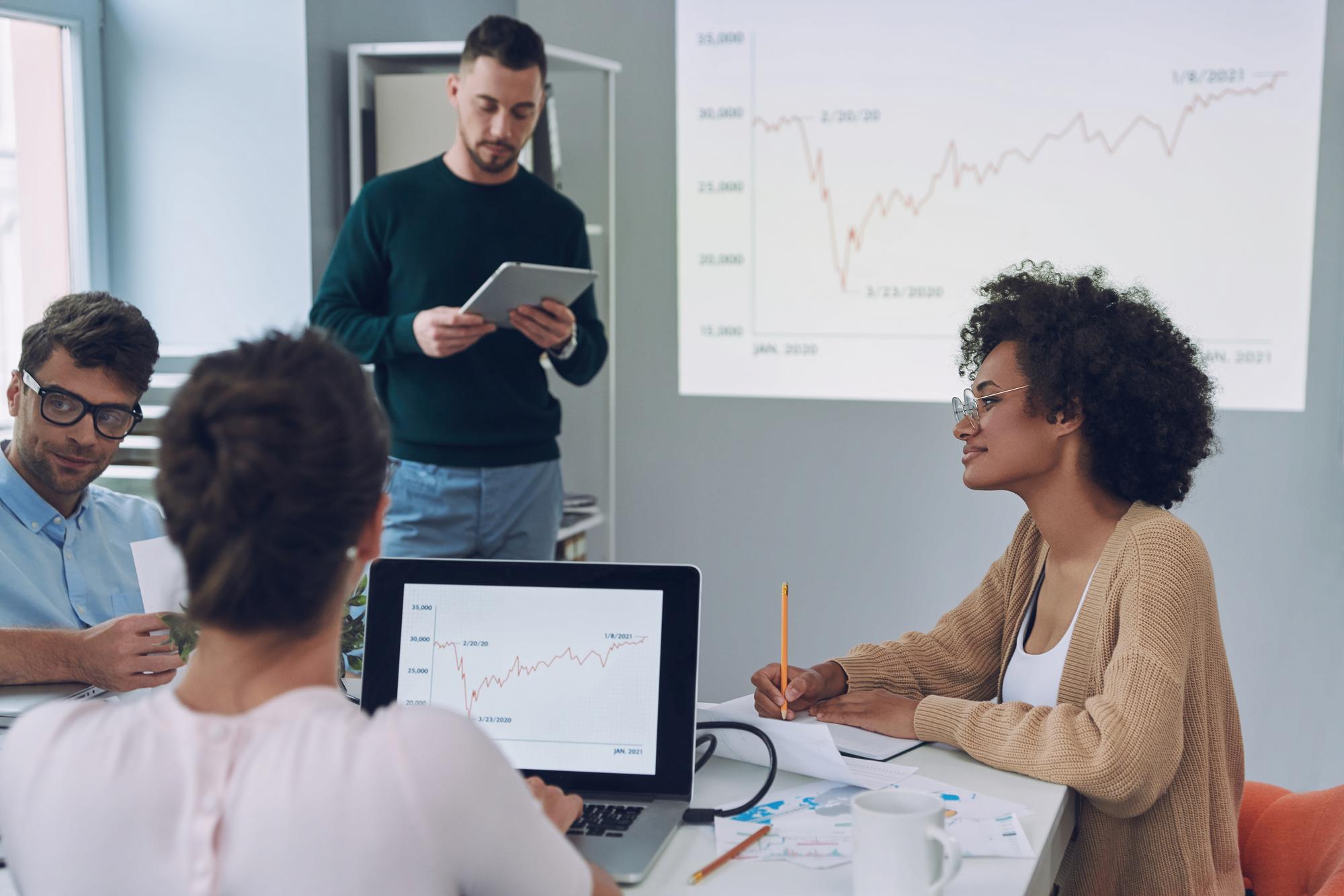 Equipe de desenvolvedores e gestores em uma sessão de mentoria conduzida por consultores, com foco em colaboração e produtividade.